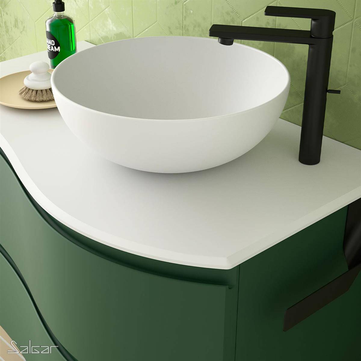 Modernes Badezimmermöbel mit einem weißen Aufsatzwaschbecken, mattschwarzer Armatur und dunkelgrünem Schrank vor hellgrünen gekachelten Wänden.