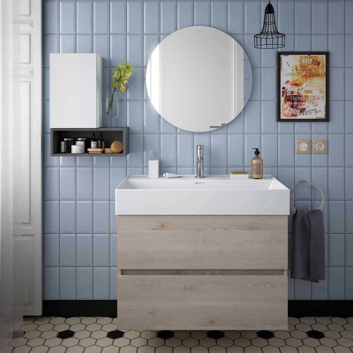 Modernes Badezimmerwaschtisch mit rundem Spiegel, Wandschrank, Regal, Rahmenkunst und Handtuchring an blauer gefliester Wand und gemustertem Boden.