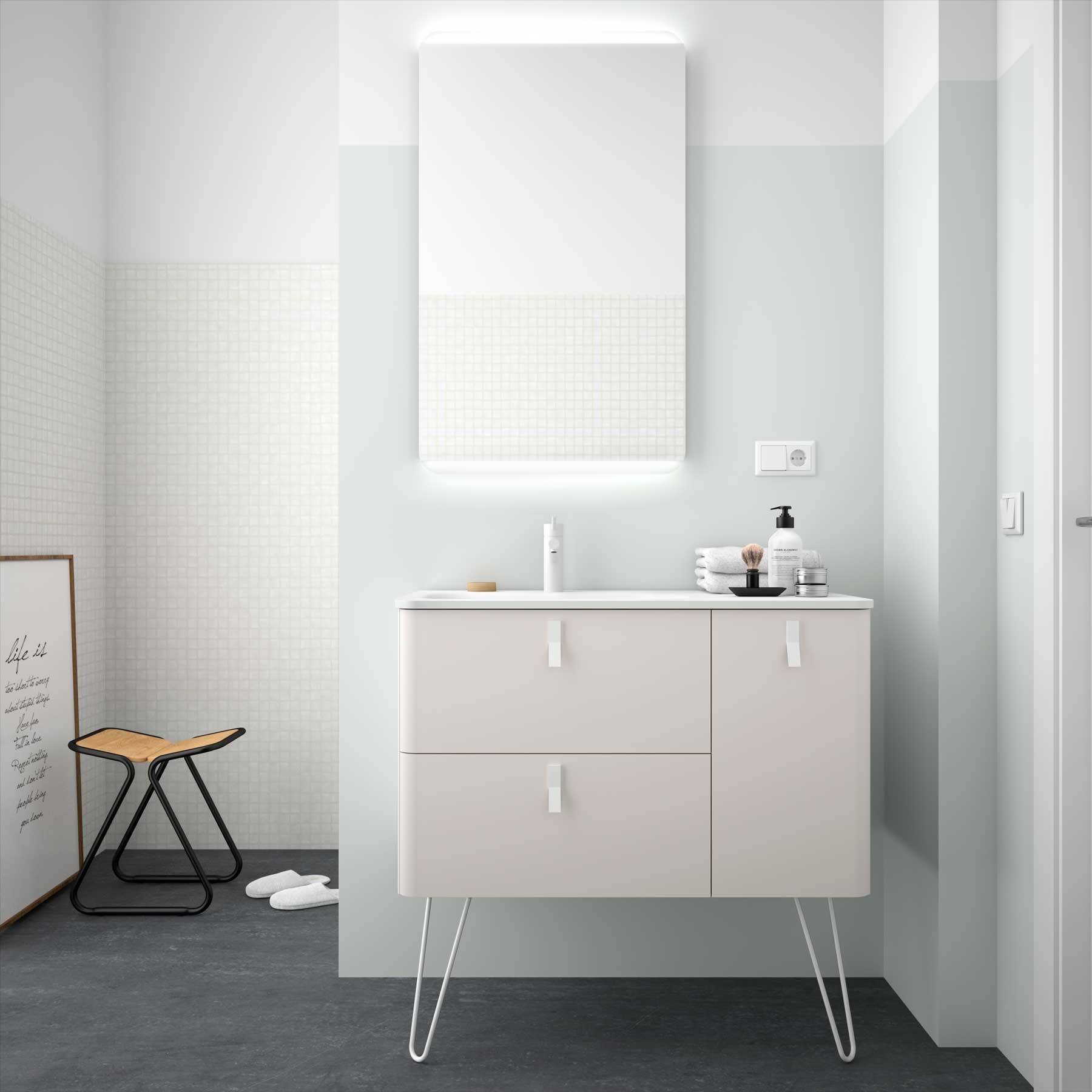 Ein modernes Badezimmer zeigt einen weißen Waschtisch mit einem beleuchteten Spiegel darüber, minimalistische Dekoration und einen kleinen schwarzen Hocker auf Schieferboden.