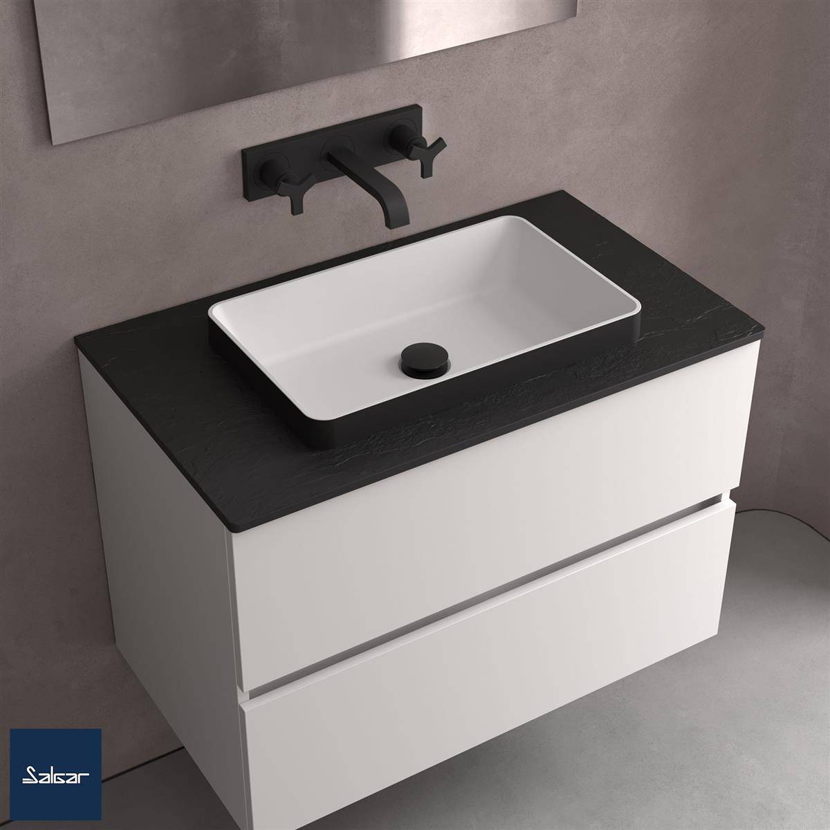 Modernes weißes Badezimmerwaschtisch mit schwarzer Arbeitsplatte, integriertem rechteckigem Waschbecken, schwarz wandmontiertem Wasserhahn und zwei Schubladen vor einer grau gefliesten Wand.