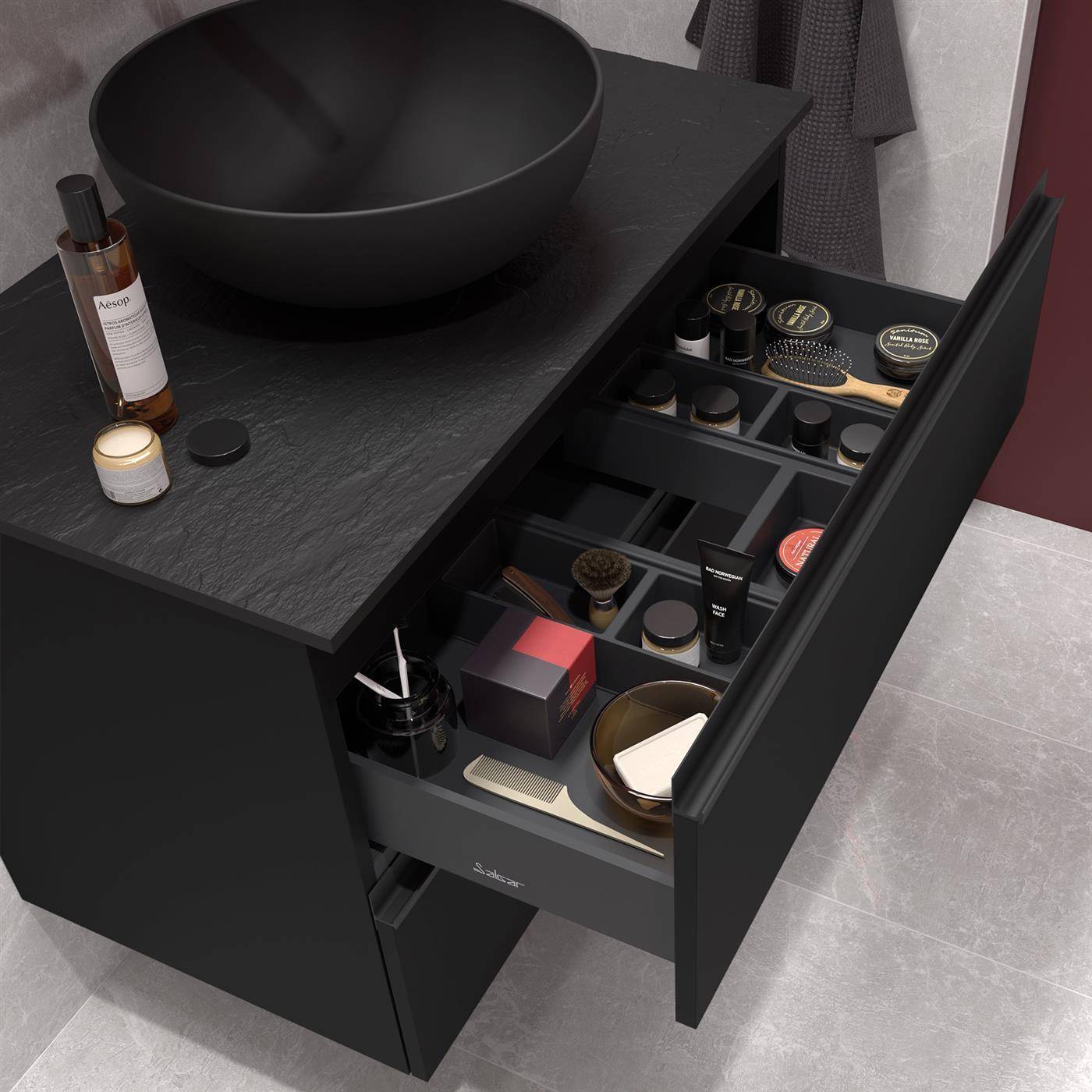 Schwarzes Badezimmerregal mit rundem Waschbecken, offener Schubladenorganizer mit Kosmetik- und Toilettenprodukten sowie einer Flasche und einer Kerze auf der Arbeitsplatte.
