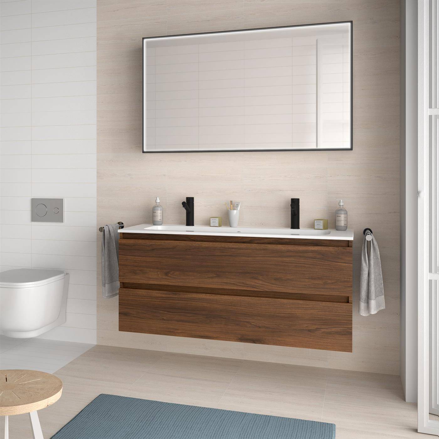 Modernes Badezimmer mit an der Wand montiertem Holz-Waschtisch, großem Spiegel, Toilette und blauer Badmatte; Handtücher hängen auf beiden Seiten.