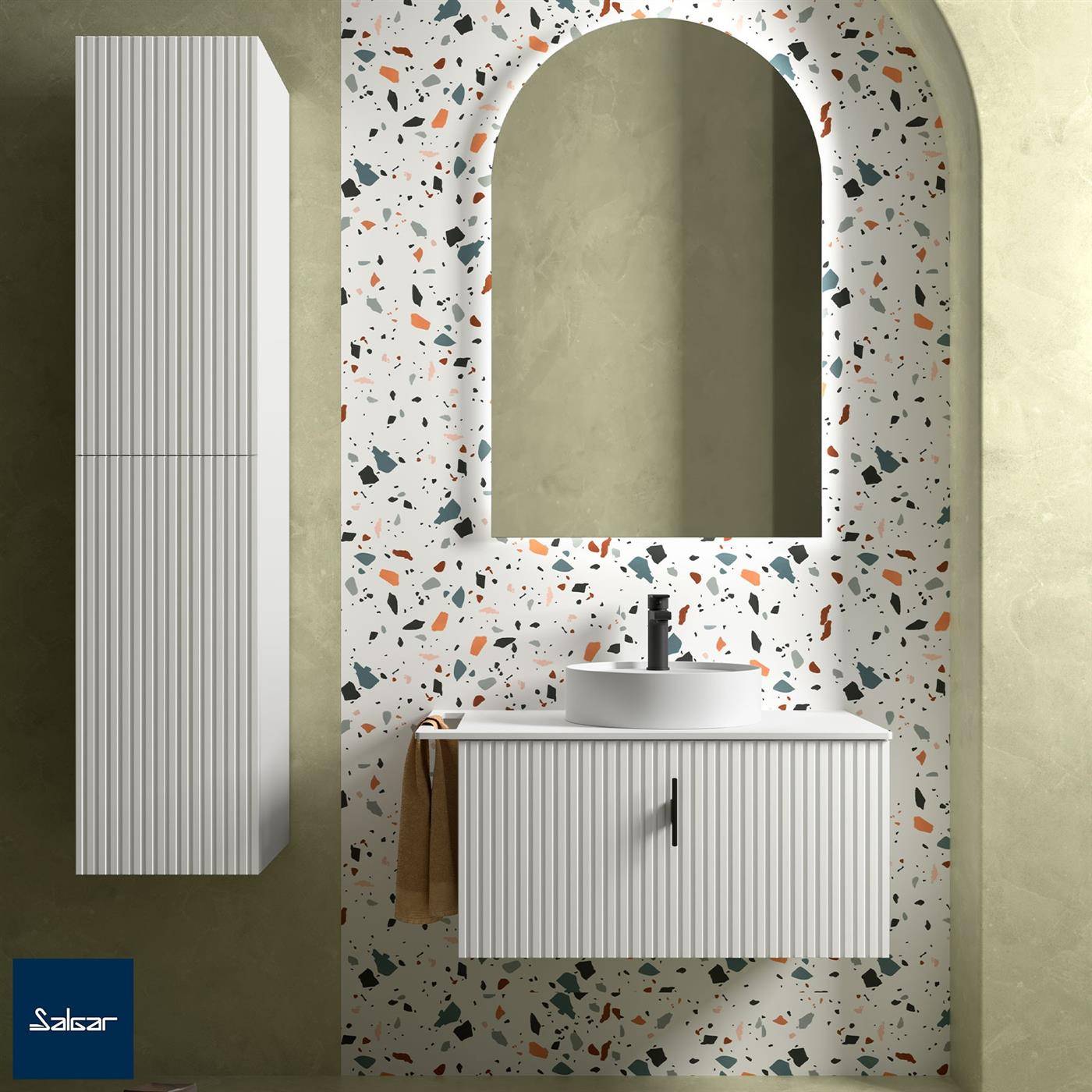 Modernes Badezimmerwaschtisch mit geripptem weißem Schrank, rundem Waschbecken und gewölbtem Spiegel vor Wandfliesen mit Terrazzo-Muster.