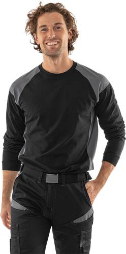 Eine Person, die ein schwarzes und graues Langarmshirt trägt, mit entspannten Armen an den Seiten und dem Fokus auf einen Oberkörper-Bekleidungsstil.