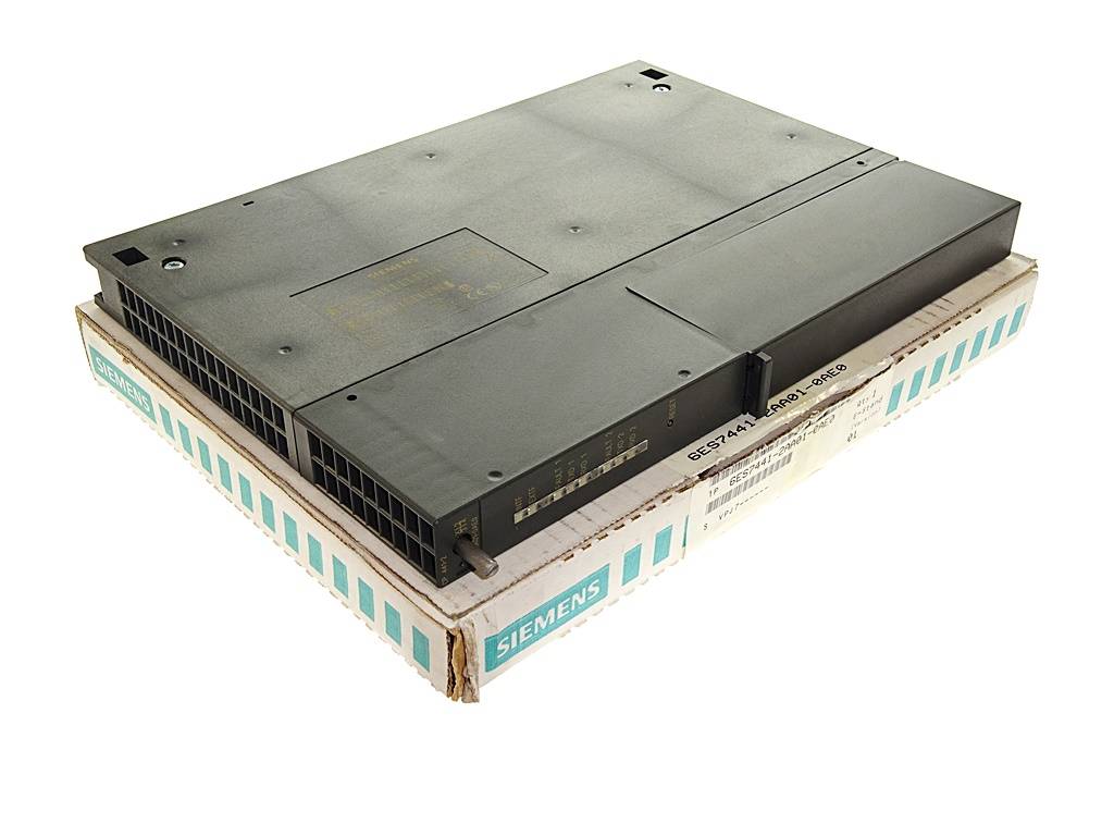 Graue industrielle Elektronikbaugruppe von Siemens, auf einer Siemens-Kartonverpackung liegend, in Dreiviertelansicht vor weißem Hintergrund dargestellt.
