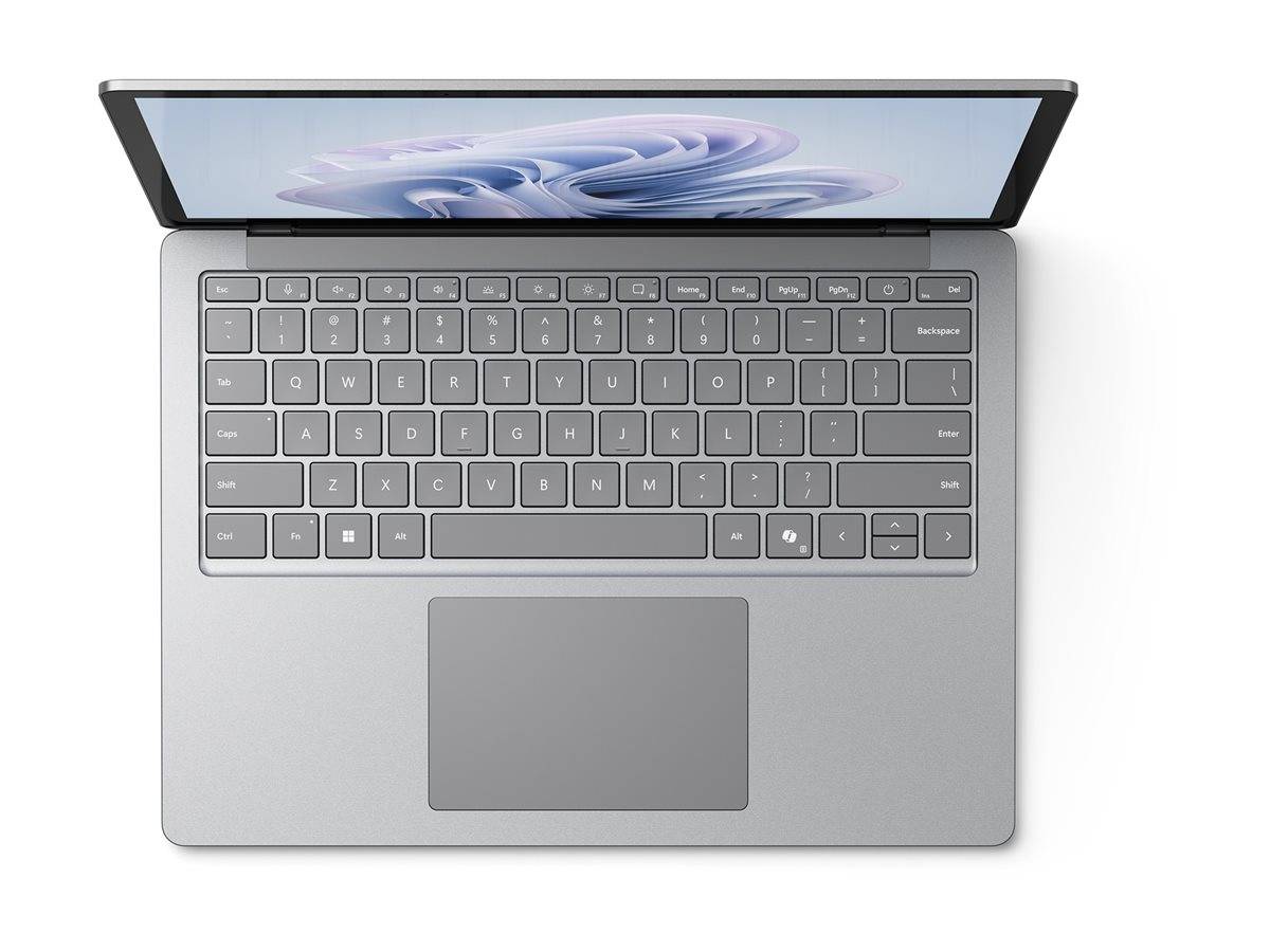 Ein silberner Laptop mit einer QWERTZ-Tastatur, großem Trackpad und einem leicht geöffneten Bildschirm, der ein subtiles, abstraktes Wellendesign zeigt.