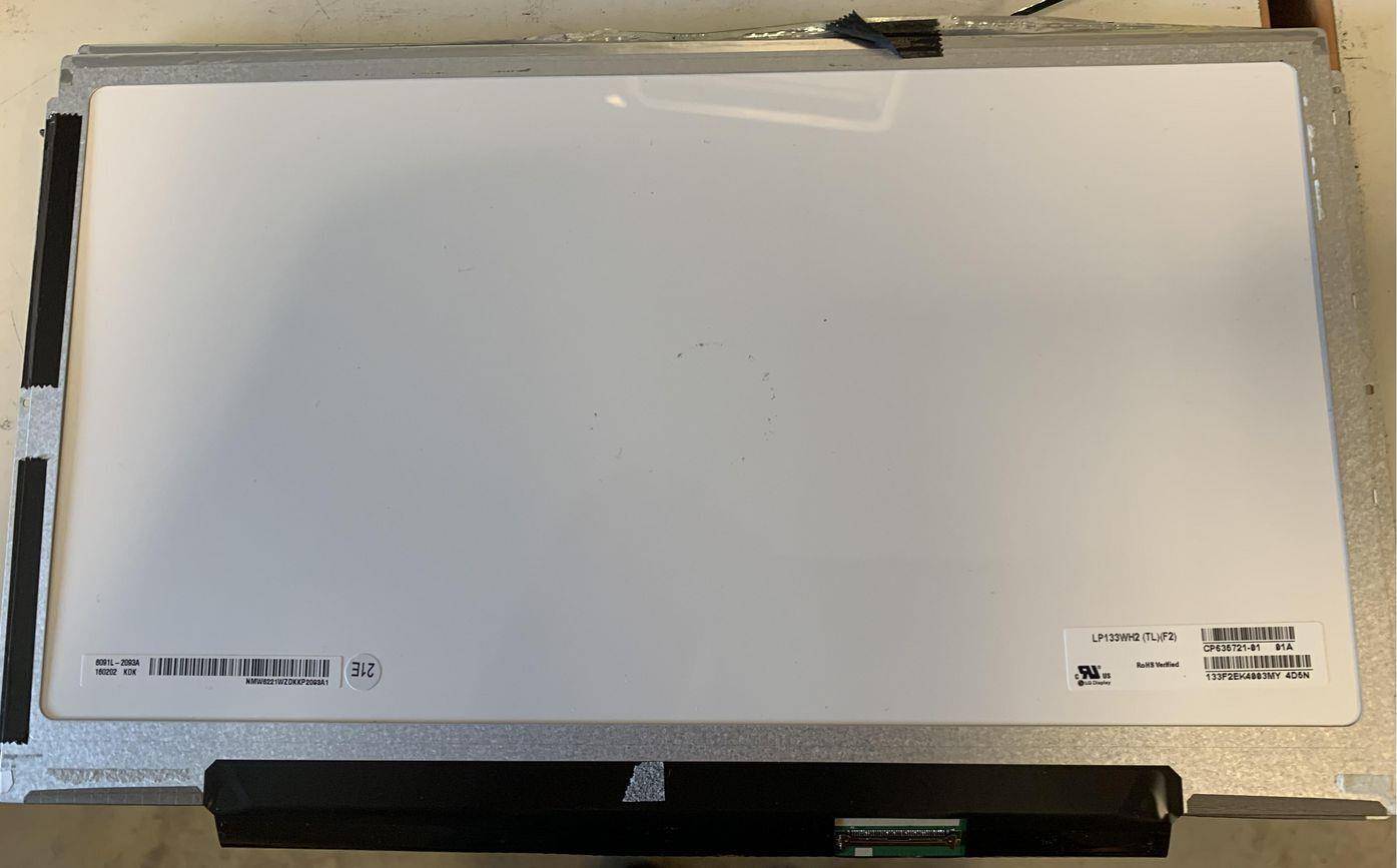 Ein weißer elektronischer Bildschirm, der auf einer Oberfläche ruht, mit einer sichtbaren Leiterplatte und Beschriftungen, die Modellnummer und Herstellerangaben anzeigen.