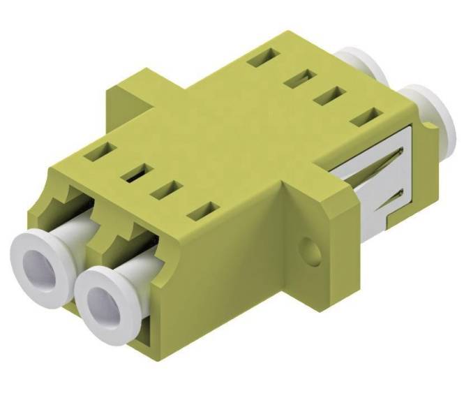 Ein grüner rechteckiger Glasfaseradapter mit zwei weißen Öffnungen und Metallclips an den Seiten, der zum Verbinden von Glasfasern verwendet wird.
