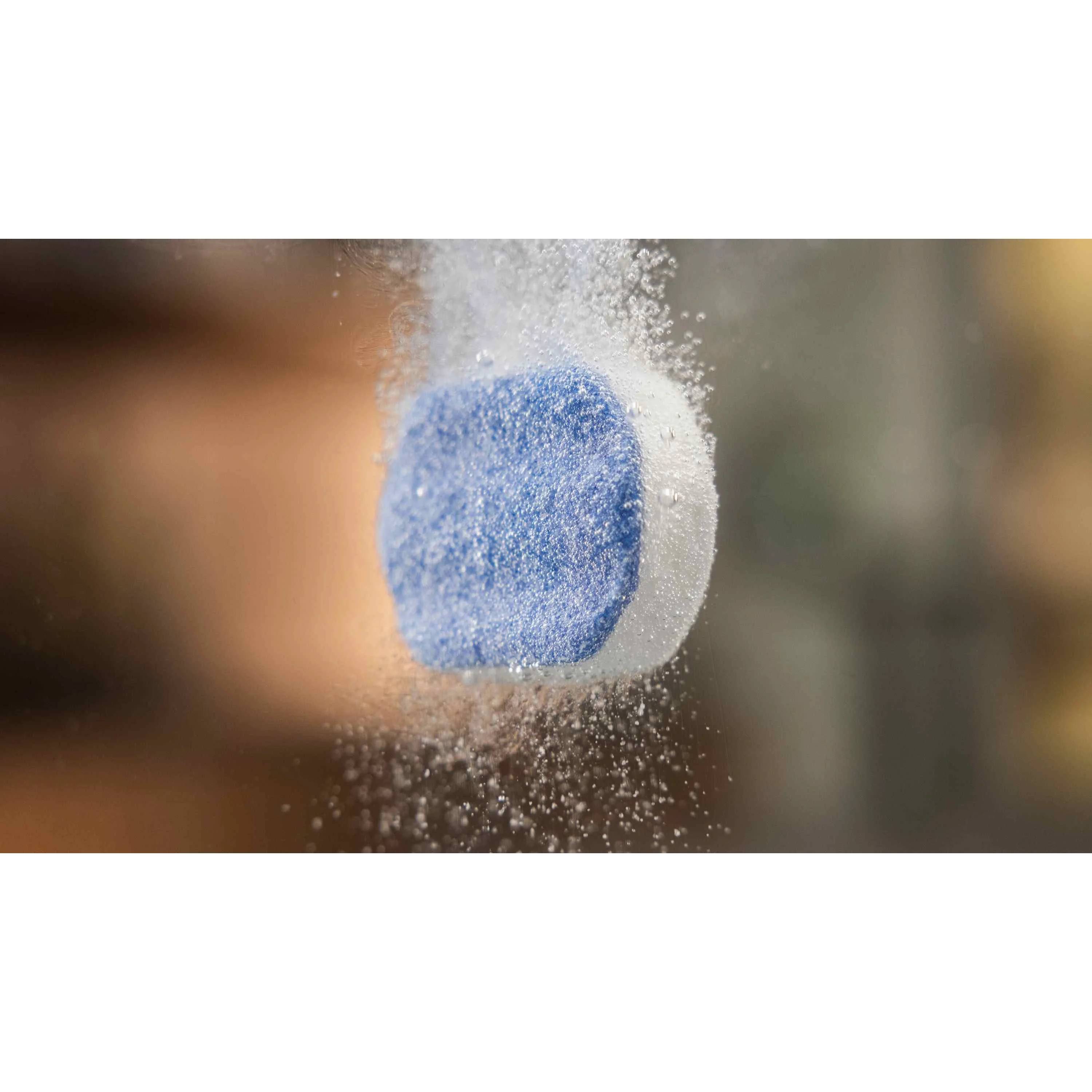 Blau-weißer Zuckerwürfel, der in der Luft aufgelöst oder zerfällt, vor unscharfem Hintergrund.