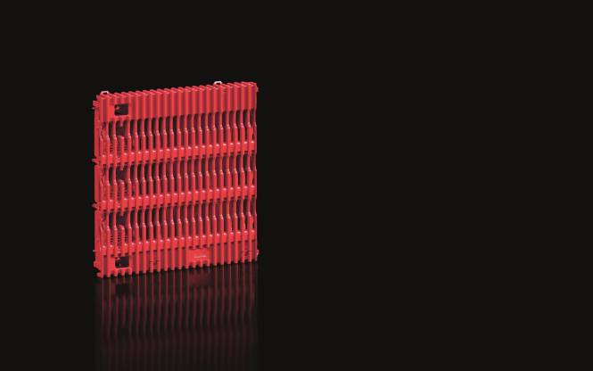 Ein rotes, geripptes, rechteckiges Objekt mit einer strukturierten Oberfläche vor schwarzem Hintergrund, das subtil Licht an seiner Basis reflektiert.