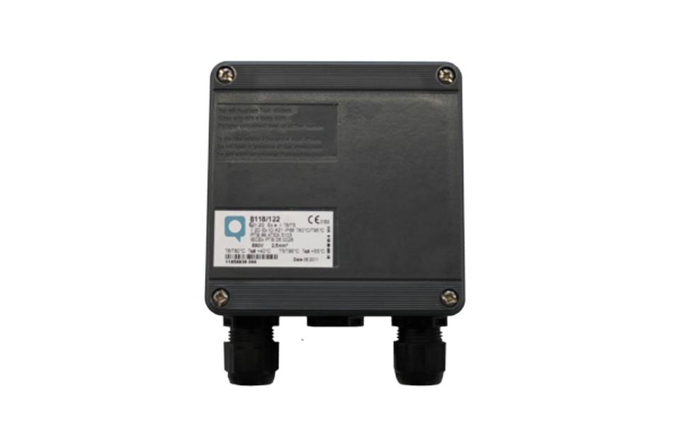 Eine kleine, dunkelgraue elektrische Verteilerdose mit zwei Kabeldurchführungen und einem sichtbaren Etikett mit Modellnummer und elektrischen Spezifikationen.