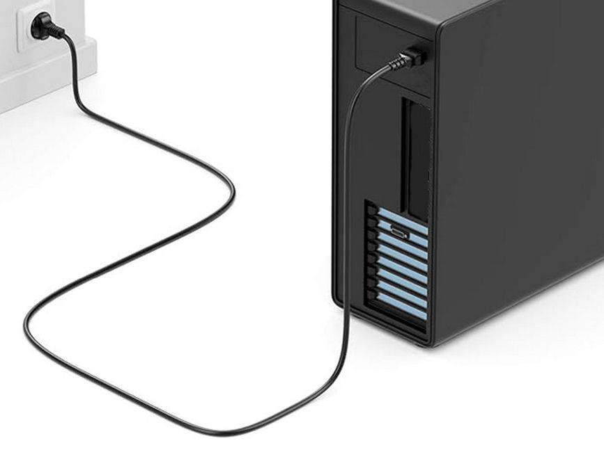Schwarzer Desktop-Computer-Turm, der mit einem Stromkabel an eine Wandsteckdose angeschlossen ist