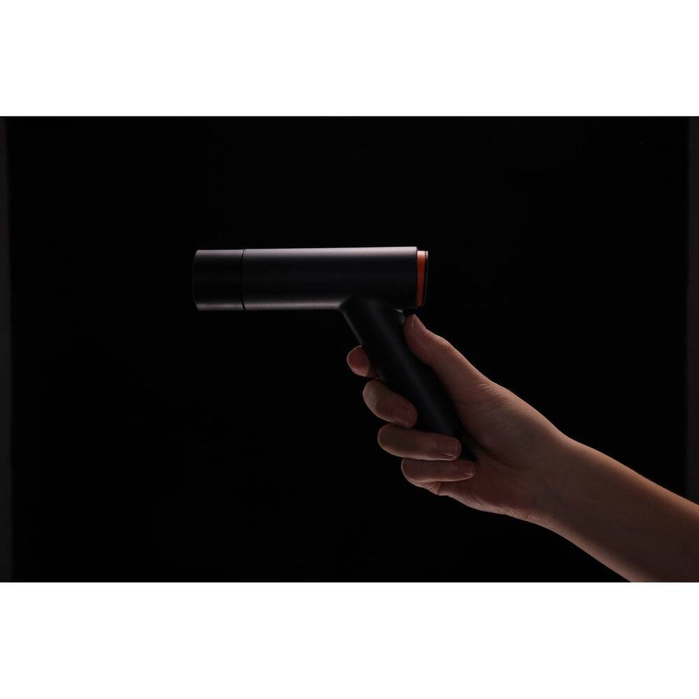 Eine Hand hält ein elegantes, schwarzes tragbares Gerät, das einem Haartrockner ähnelt, vor einem dunklen Hintergrund. Das Gerät wirkt kompakt und modern.