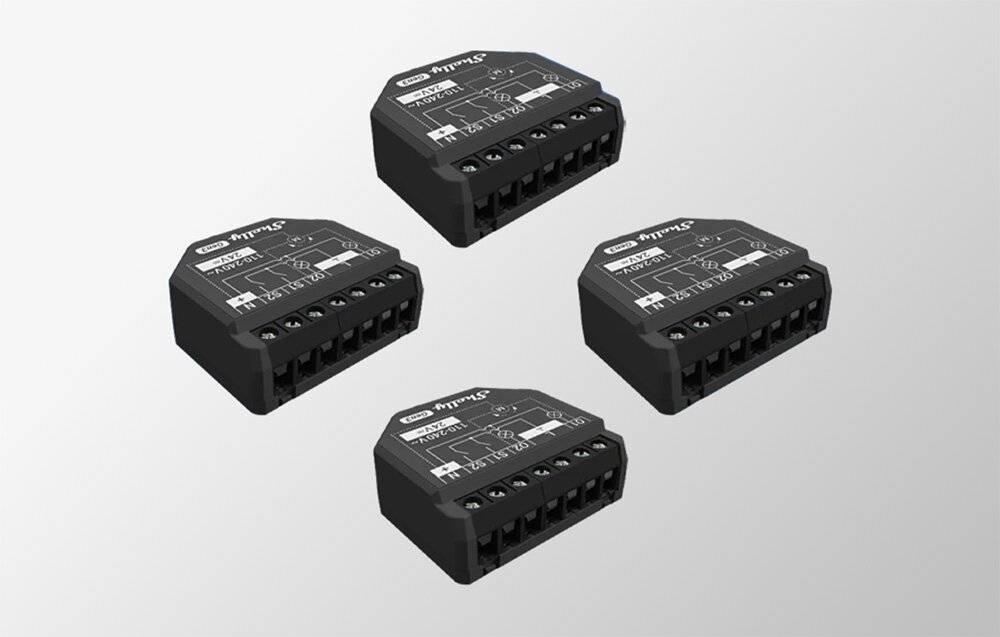 Vier schwarze elektronische Module mit beschrifteten Anschlüssen sind in einem Raster angeordnet. Jedes Modul hat ein kompaktes Design und sichtbare Schraubklemmen.