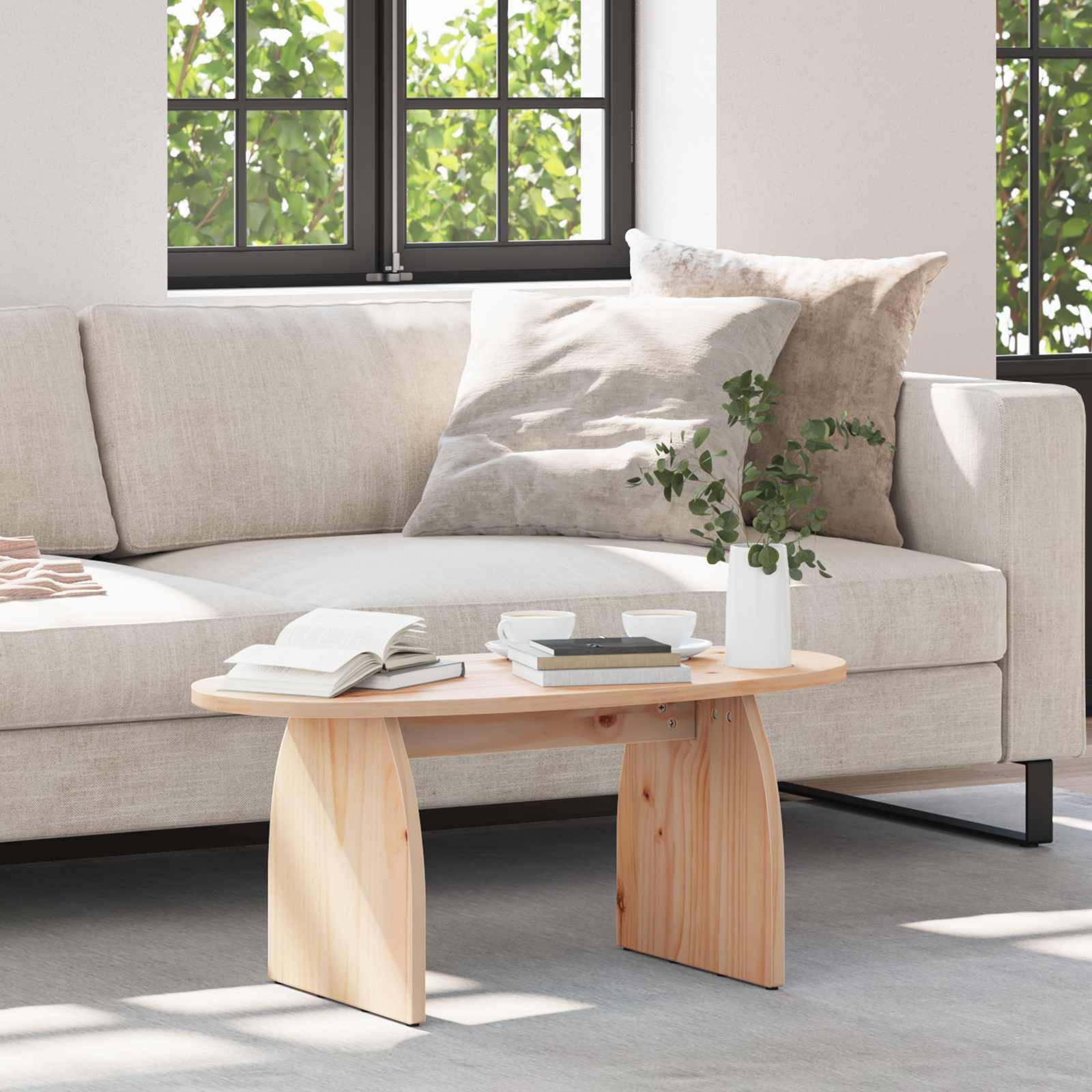Ein moderner Wohnraum zeigt ein hellbeiges Sofa mit einem passenden Kissen, einen Holzcouchtisch mit Büchern und einer Pflanze und zwei Fenster.