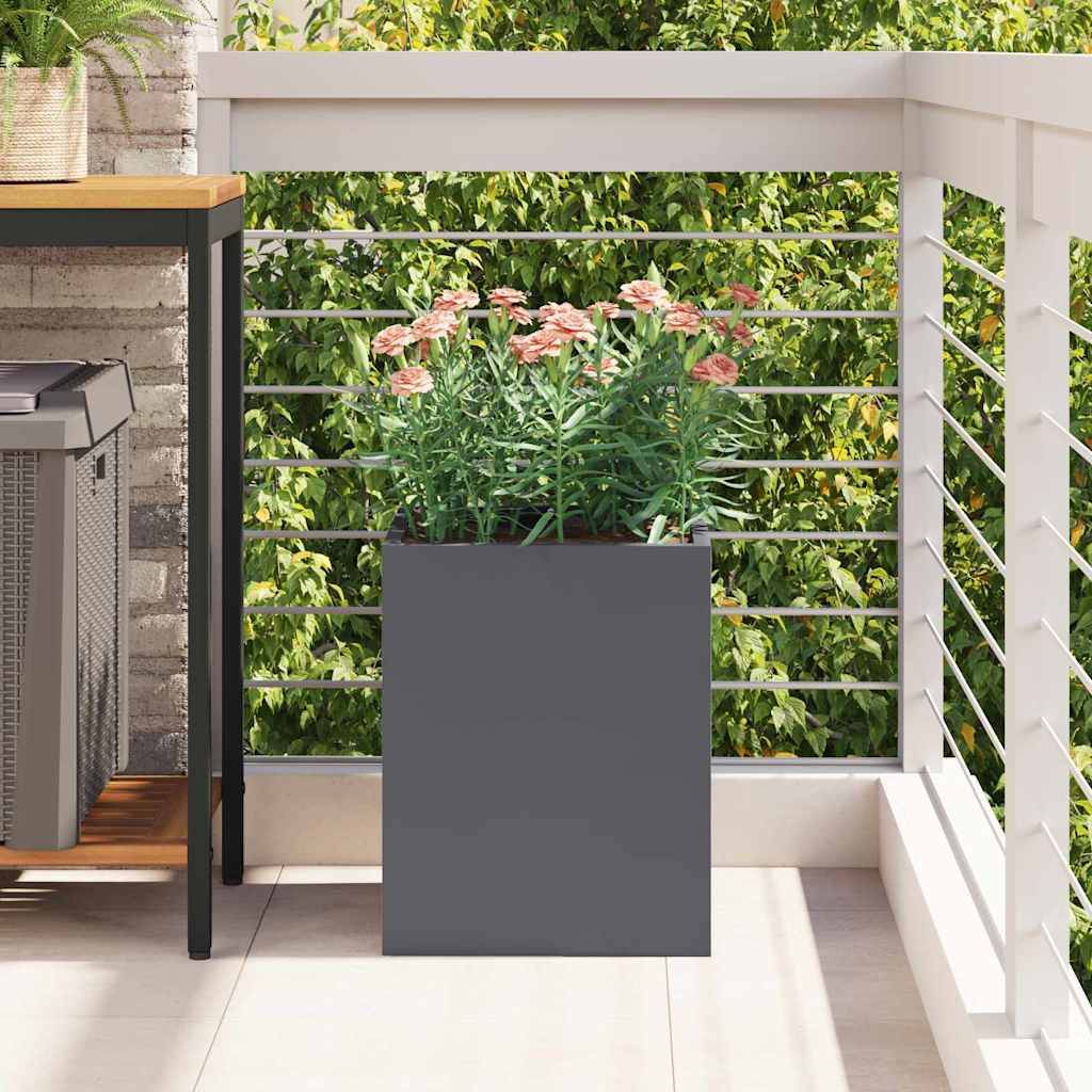 Ein grauer Blumentopf mit rosa Blumen auf einem Balkon neben einem Tisch, umgeben von einem weißen Geländer und Grünpflanzen im Hintergrund.