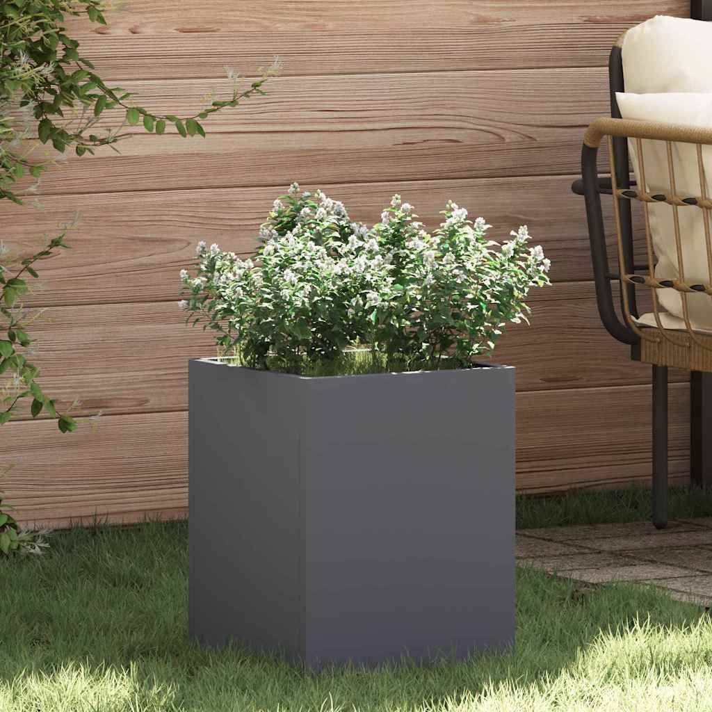 Eine grüne Topfpflanze in einem quadratischen grauen Pflanzgefäß steht auf einer Terrasse neben einem Holzzaun und einem Outdoor-Stuhl und schafft eine ruhige Gartenkulisse.