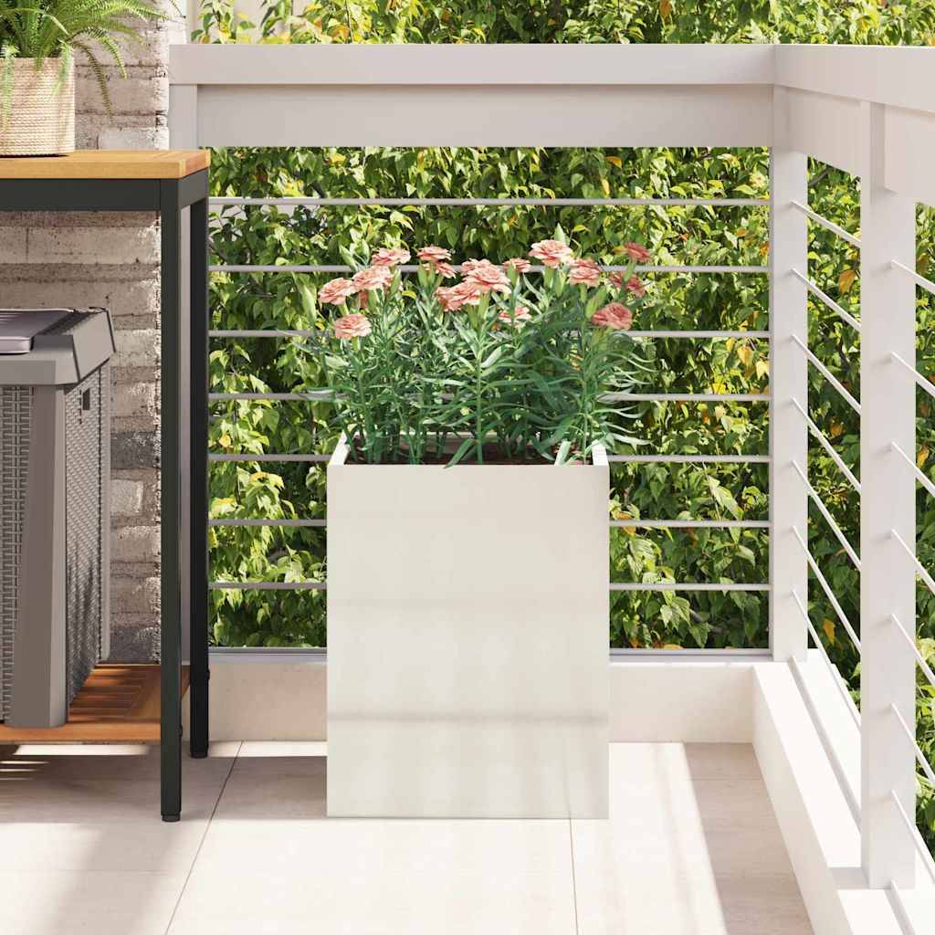 Ein kleiner Balkon mit einer Topfpflanze auf gefliesten Boden, einem Holztisch mit einem grauen Behälter und weißem Geländer, der auf grünes Blattwerk hinausblickt.