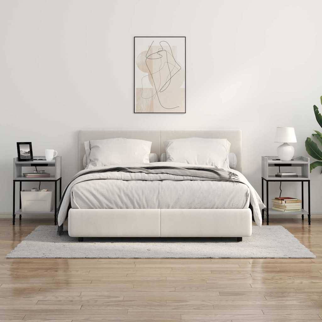Minimalistisches modernes Schlafzimmer mit einem weißen Bett, passenden Nachttischen und Lampen, abstrakter Wandkunst und einer Pflanze auf der rechten Seite.