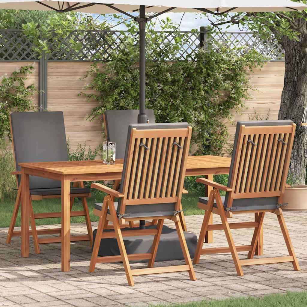 Eine Terrassenessgruppe mit einem Holztisch und vier Stühlen unter einem Sonnenschirm, umgeben von Grünpflanzen und einem Holzzaun.