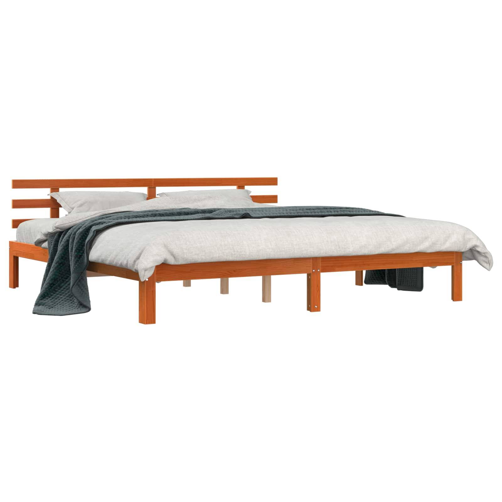 Ein Holzplattformbett mit einem Lamellenkopfteil, weißer Bettwäsche und einer dunkelgrauen Decke, die ordentlich über das Fußende des Bettes drapiert ist.