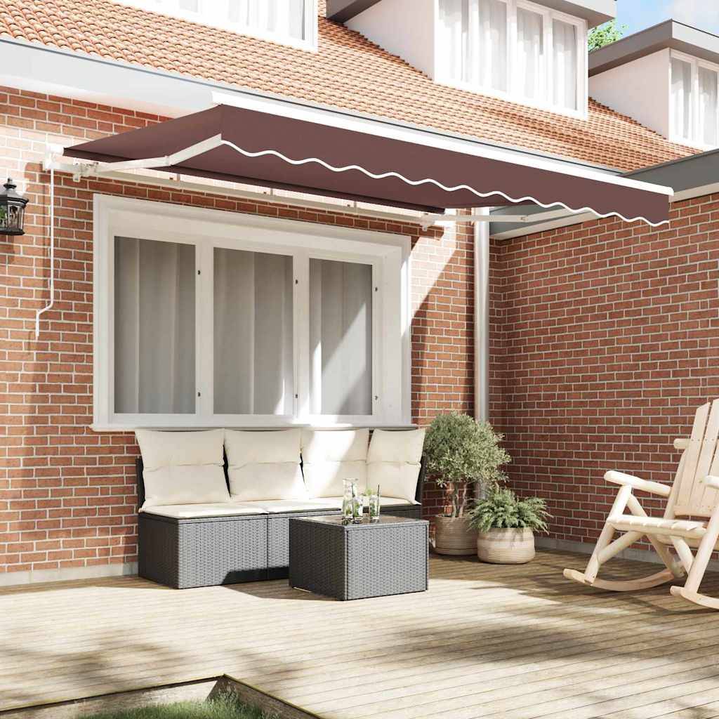 Eine Backsteinterrasse mit einem weiß gerahmten Fenster, gepolsterten Sitzgelegenheiten, einem kleinen Tisch mit Dekoration, Topfpflanzen und einem ausfahrbaren Sonnensegel darüber.