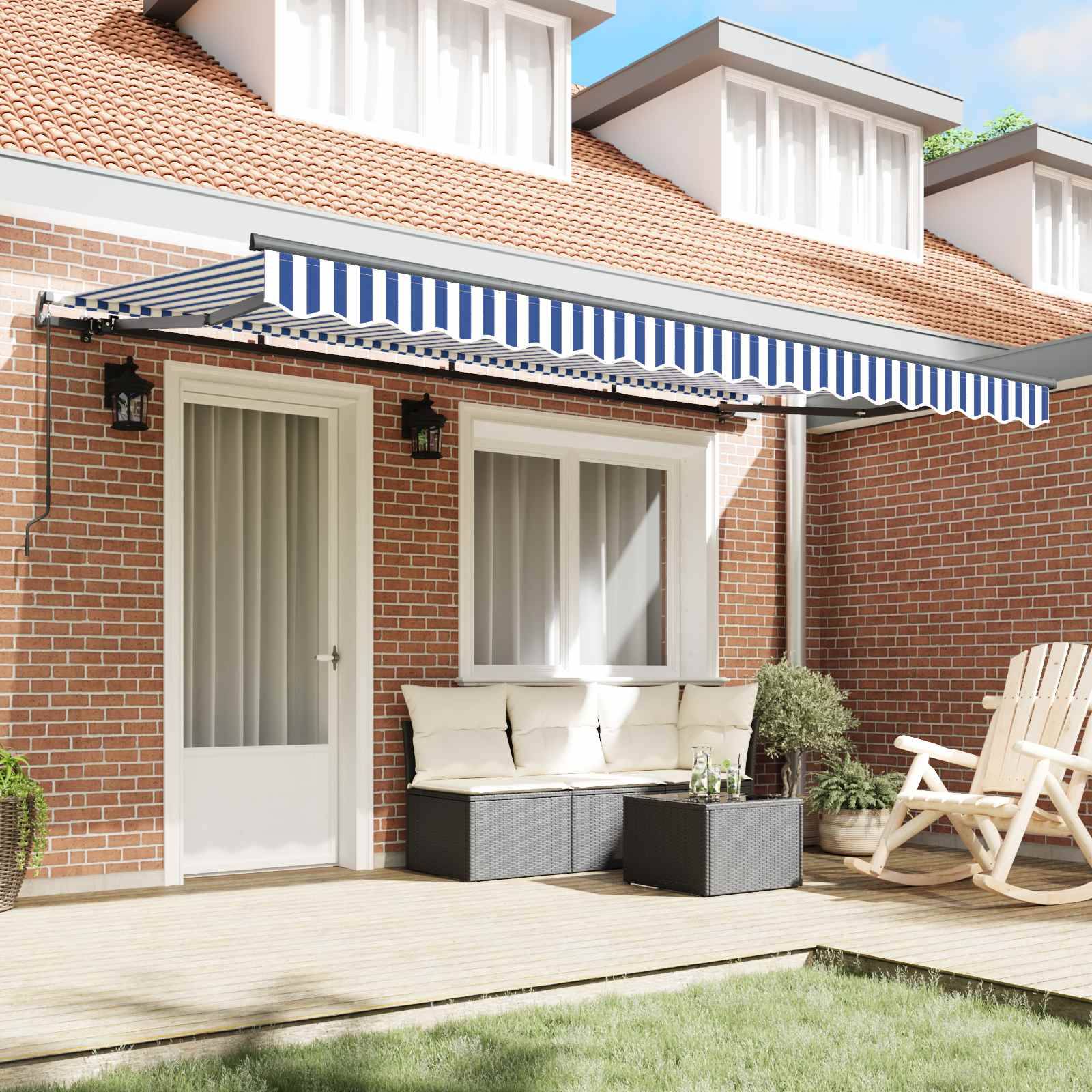 Ein Terrassenhof aus Ziegelsteinen mit blau-weiß gestreifter Markise, weißer Tür und Fenster. Ein weißer Korbstuhl, ein schwarzer Tisch und eine Bank bieten Sitzmöglichkeiten.