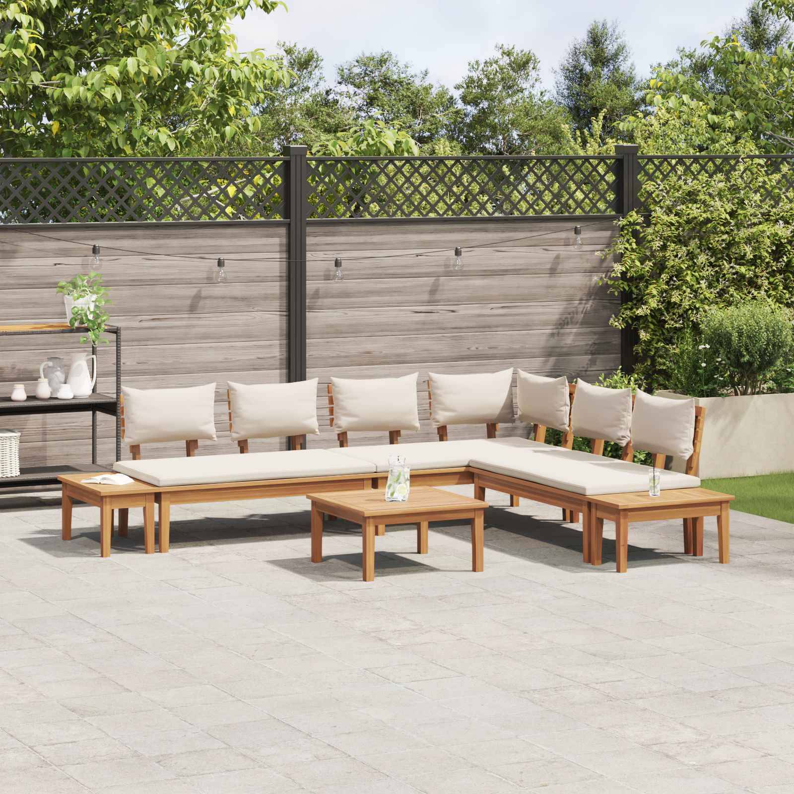 L-förmiges Außen-Terrassenmöbelset mit beigen Kissen auf einer gefliesten Terrasse vor einem Holz-Sichtschutzz zaun, umgeben von Grünflächen.