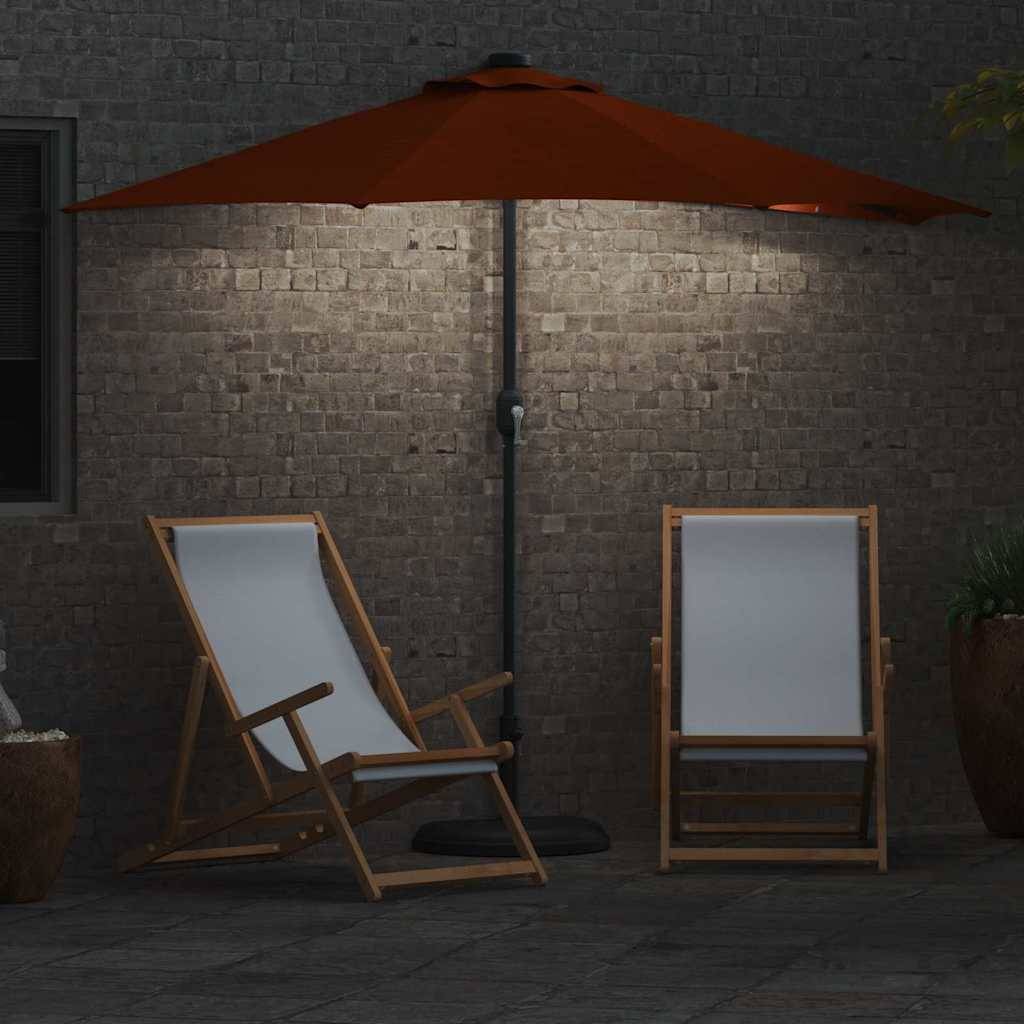 Eine Terrasse mit zwei Holzliegestühlen unter einem großen orangefarbenen Sonnenschirm. Der Bereich ist gedämpft beleuchtet, mit einer Ziegelwand und sichtbaren Topfpflanzen.