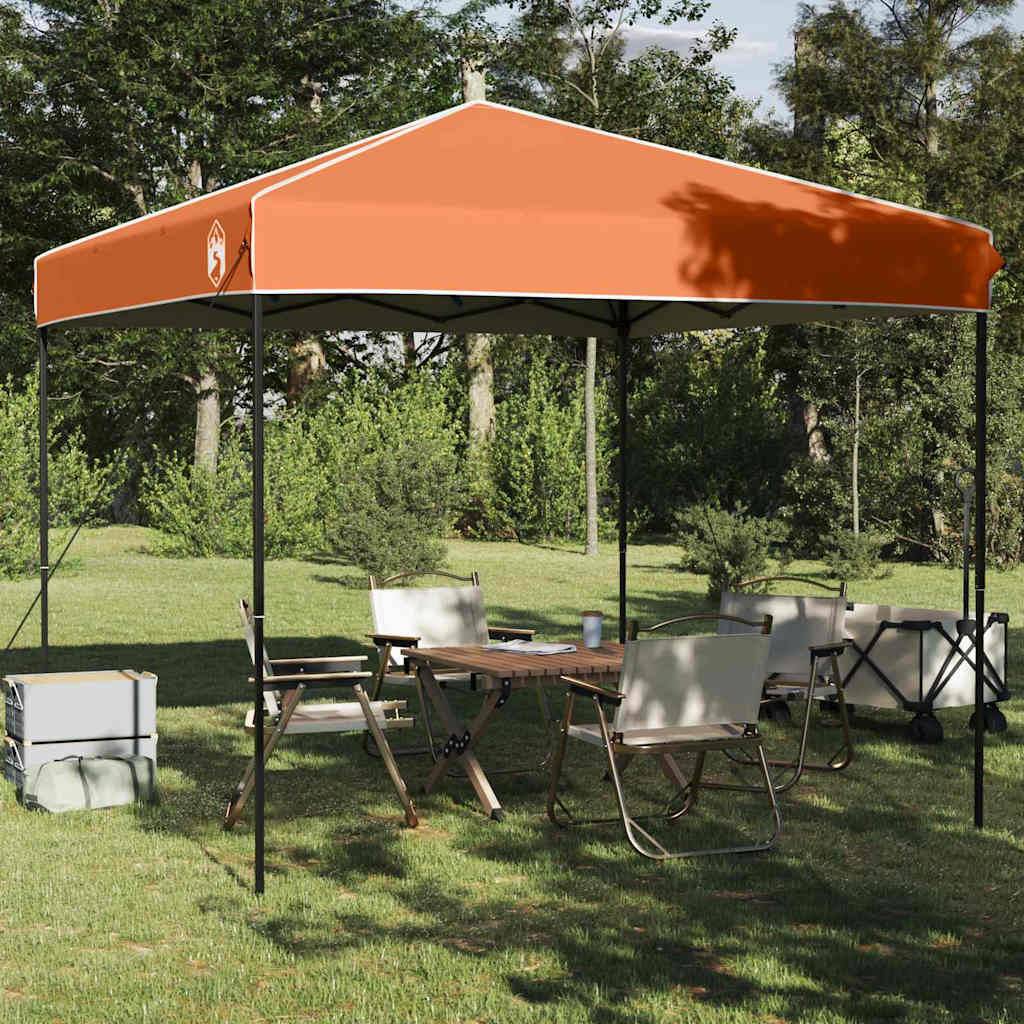 Ein Pop-up-Pavillon mit orangefarbenem Dach steht in einem grasigen Bereich, umgeben von Bäumen. Darunter sind Klappstühle und ein gedeckter Tisch platziert.