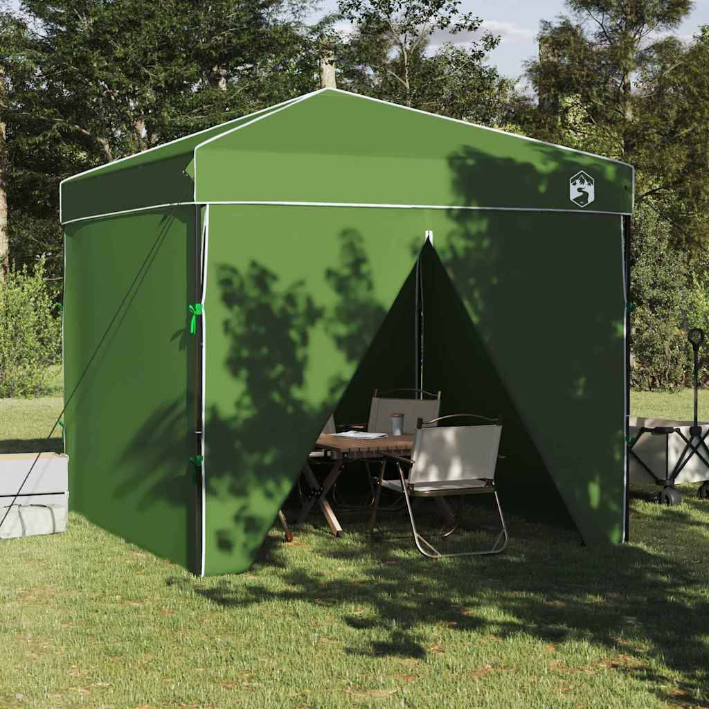 Ein grünes Outdoor-Pavillon-Zelt mit offenen Klappen, die einen Picknicktisch und Stühle offenbaren, aufgestellt auf einer Rasenfläche mit Bäumen im Hintergrund.