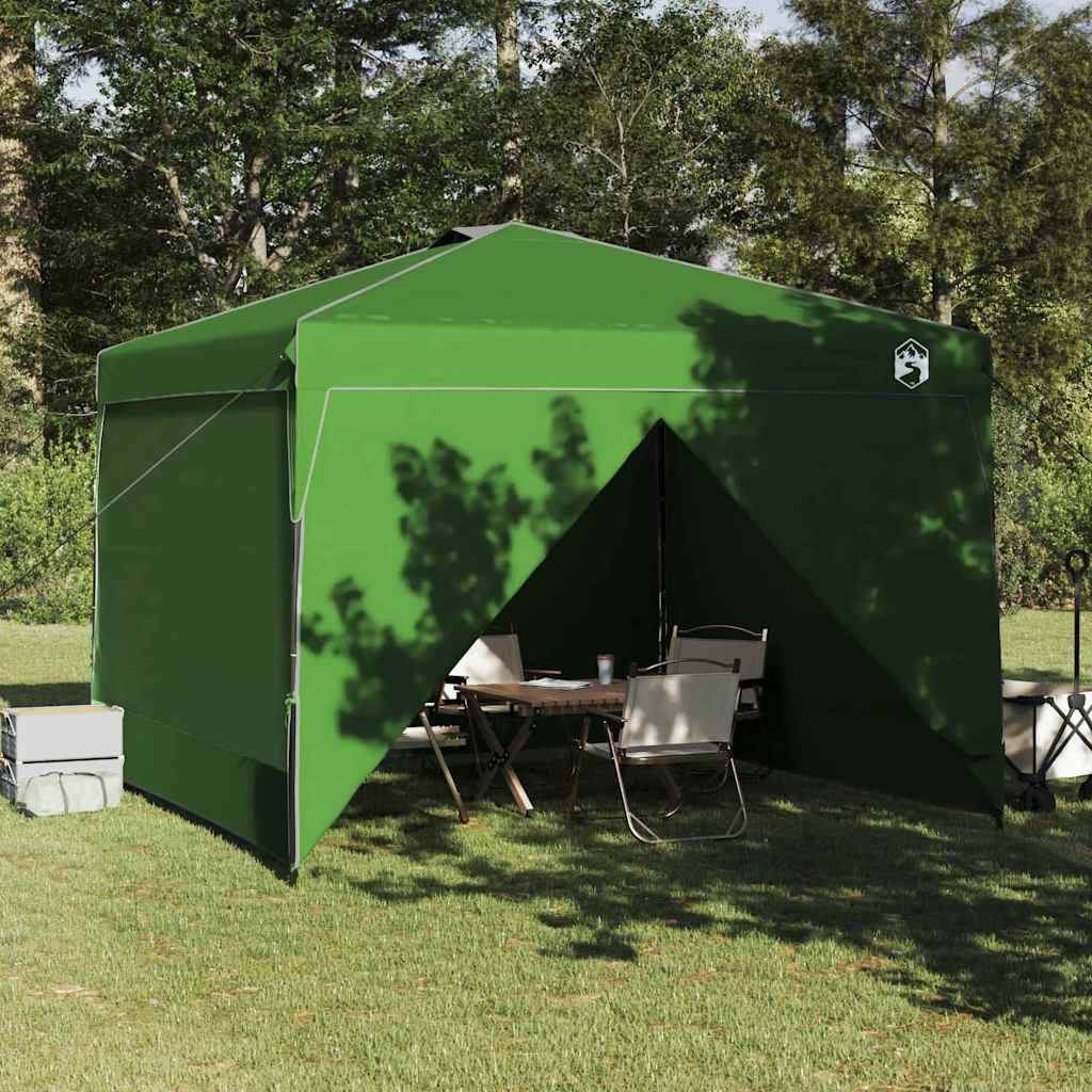 Ein grünes Outdoor-Pavillon-Zelt auf Gras mit Stühlen und einem Tisch darunter, umgeben von Bäumen.