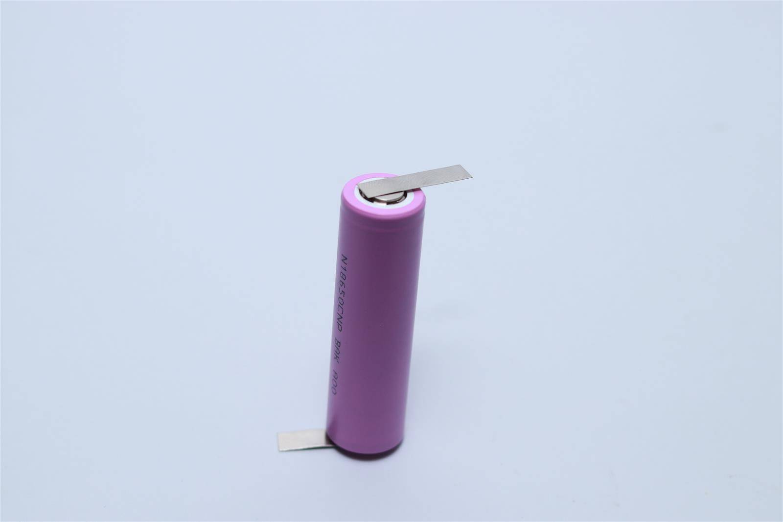 Eine rosa zylindrische Batterie, die aufrecht auf einer glatten Oberfläche steht, mit Metallanschlüssen, die von Ober- und Unterseite abstehen.