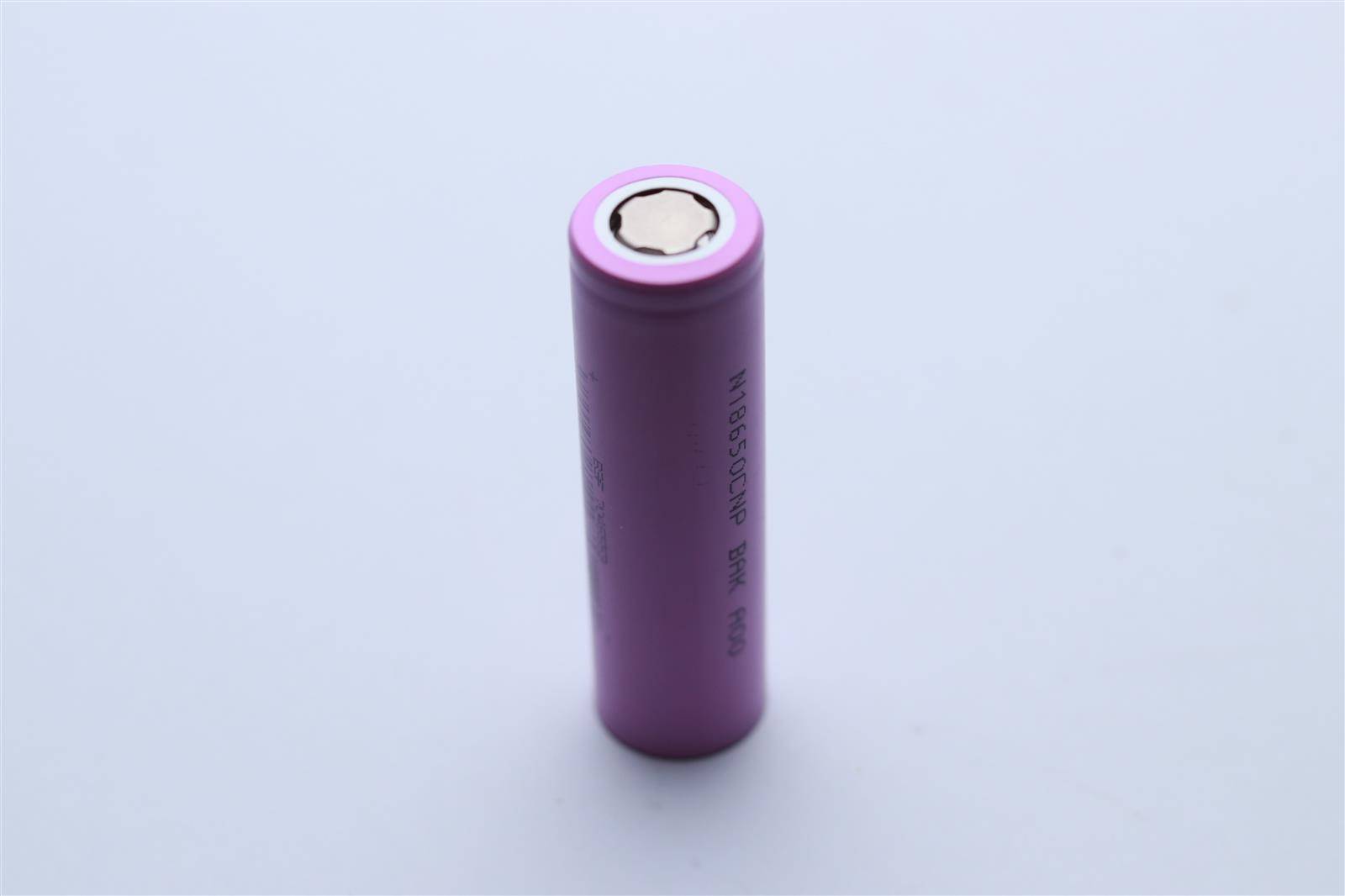 Eine lila zylindrische wiederaufladbare Batterie, die aufrecht steht und den positiven Pol sowie gedruckte Spezifikationen an der Seite zeigt.