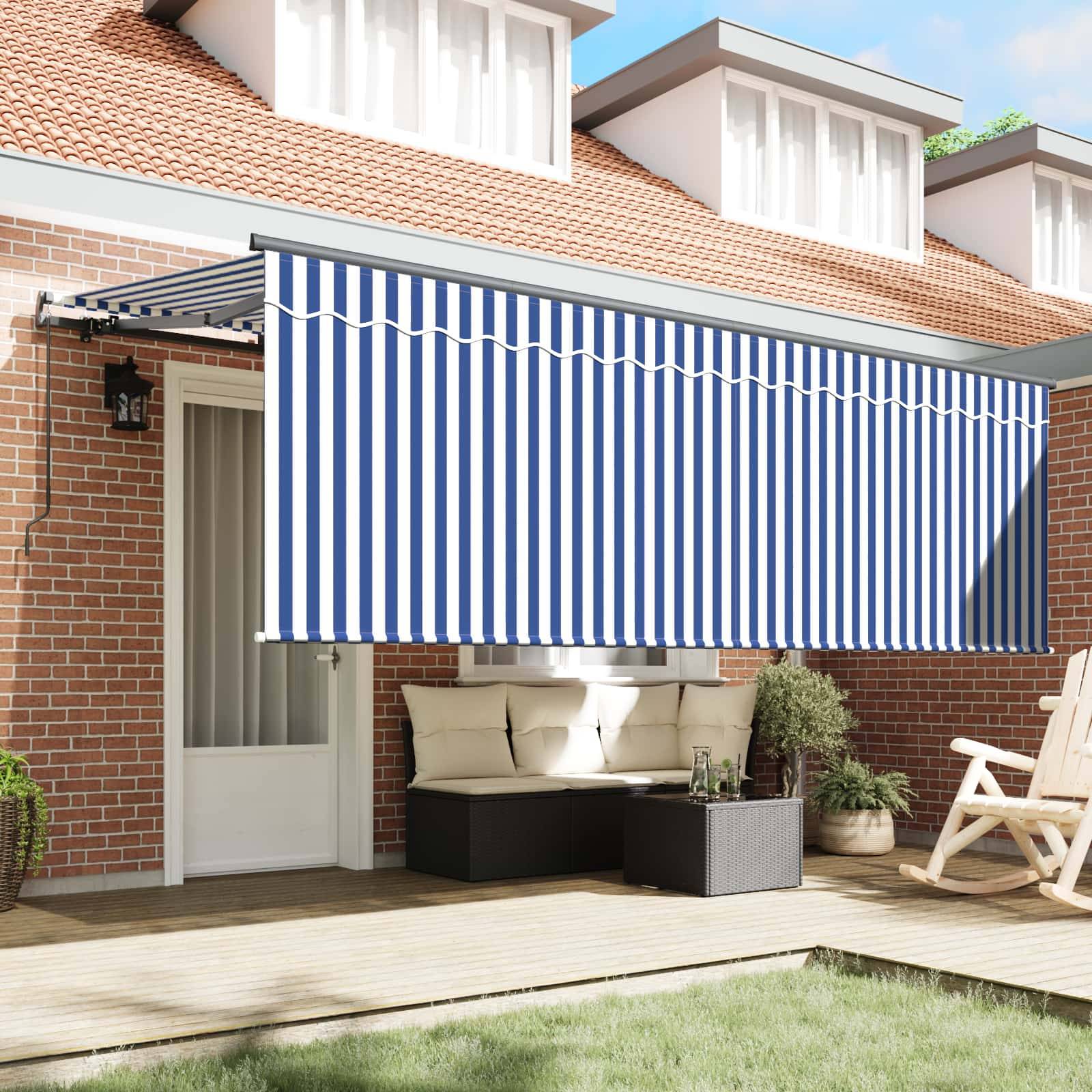Eine Terrasse mit roter Backsteinmauer, blau-weiß gestreifter einziehbarer Markise und Außenmöbeln, einschließlich zwei Stühlen und einem kleinen Tisch.