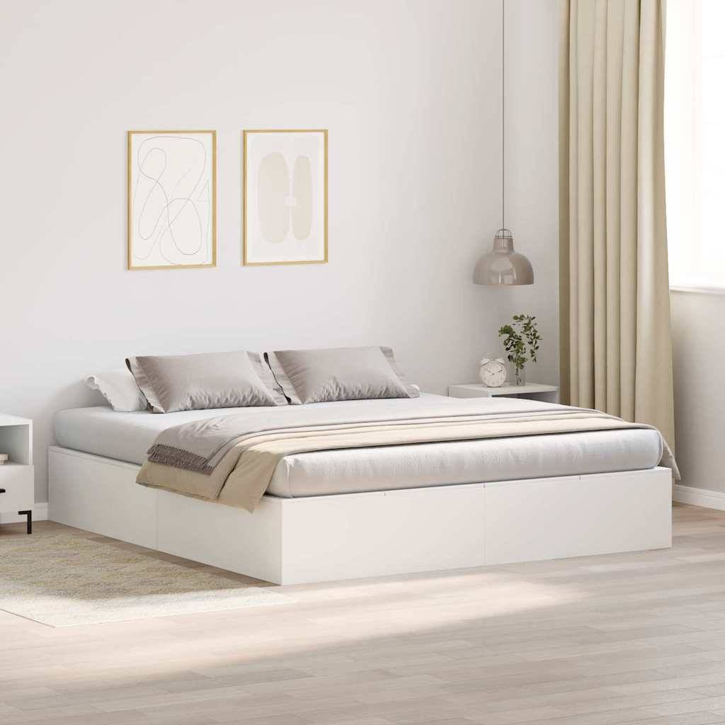 Minimalistisches Schlafzimmer mit einem niedrigen weißen Bett, beigefarbener Bettwäsche, gerahmter Wandkunst, Pendelleuchte und transparenten Vorhängen neben einem hellen Fenster.