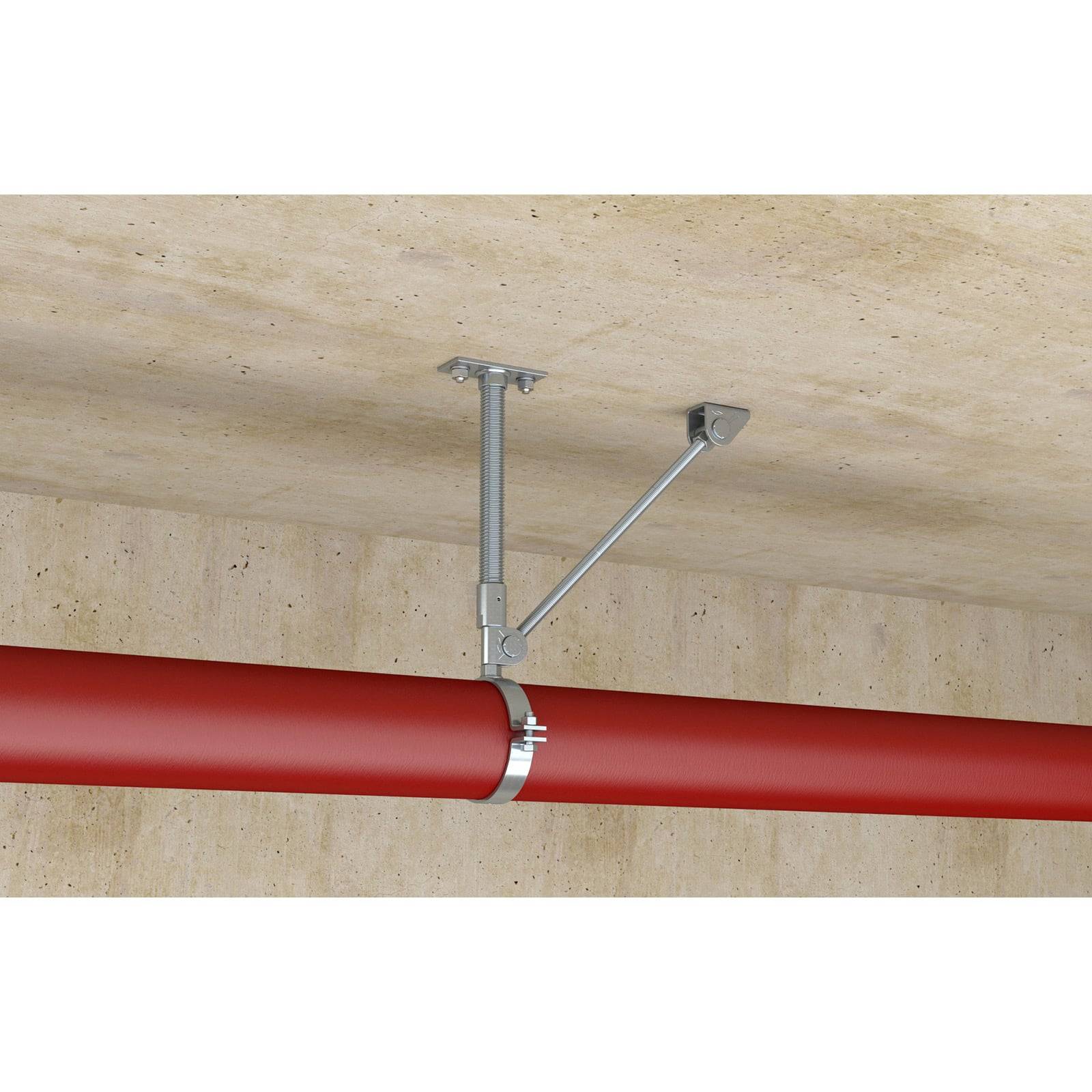 Eine rote Rohrleitung ist mit Metallklammern sicher an der Decke befestigt und zeigt ein robustes Stützsystem in einer beigen, industriellen Umgebung.