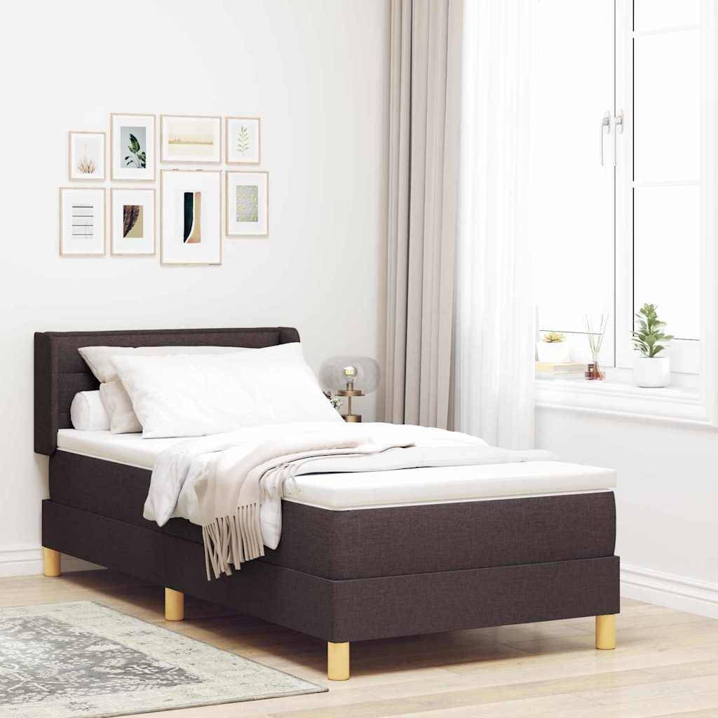 Ein sorgfältig gemachtes Bett mit dunklem Rahmen steht neben einem Fenster. Eine Reihe von kleinen gerahmten Kunstwerken hängt an der Wand über dem Bett.