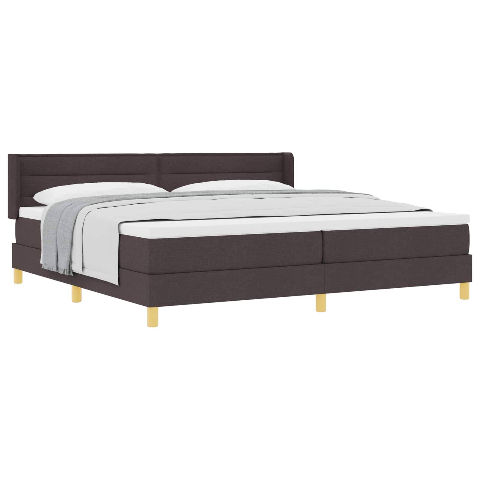 Dunkles gepolstertes Plattformbett mit weißer Bettwäsche und einer grauen Wurfdecke auf weißem Hintergrund.