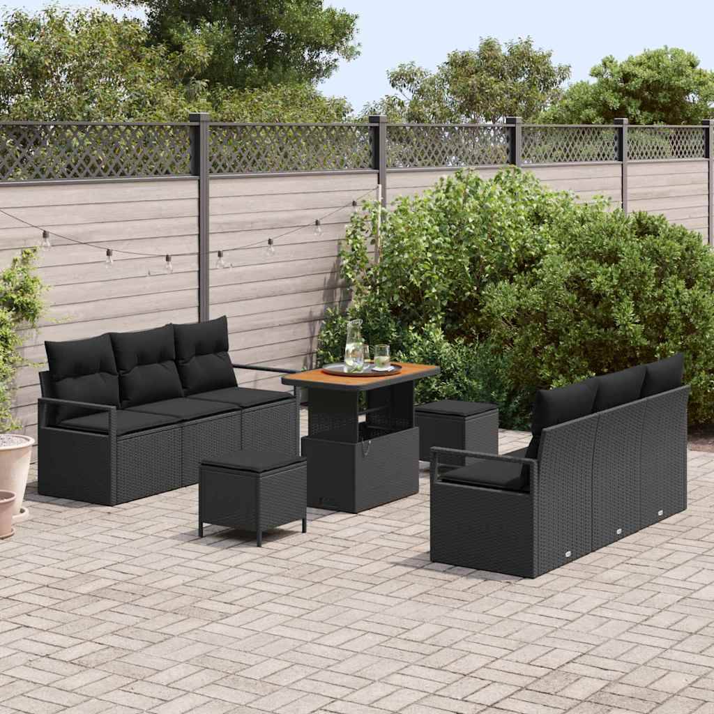 Terrassenmöbel-Set mit schwarzem Rattanmobiliar, bestehend aus einem Sofa, zwei Sesseln, einem Tisch mit Glasplatte und zwei kleinen Hockern. Umgeben von Grünpflanzen und einem Holzzaun im Hintergrund.
