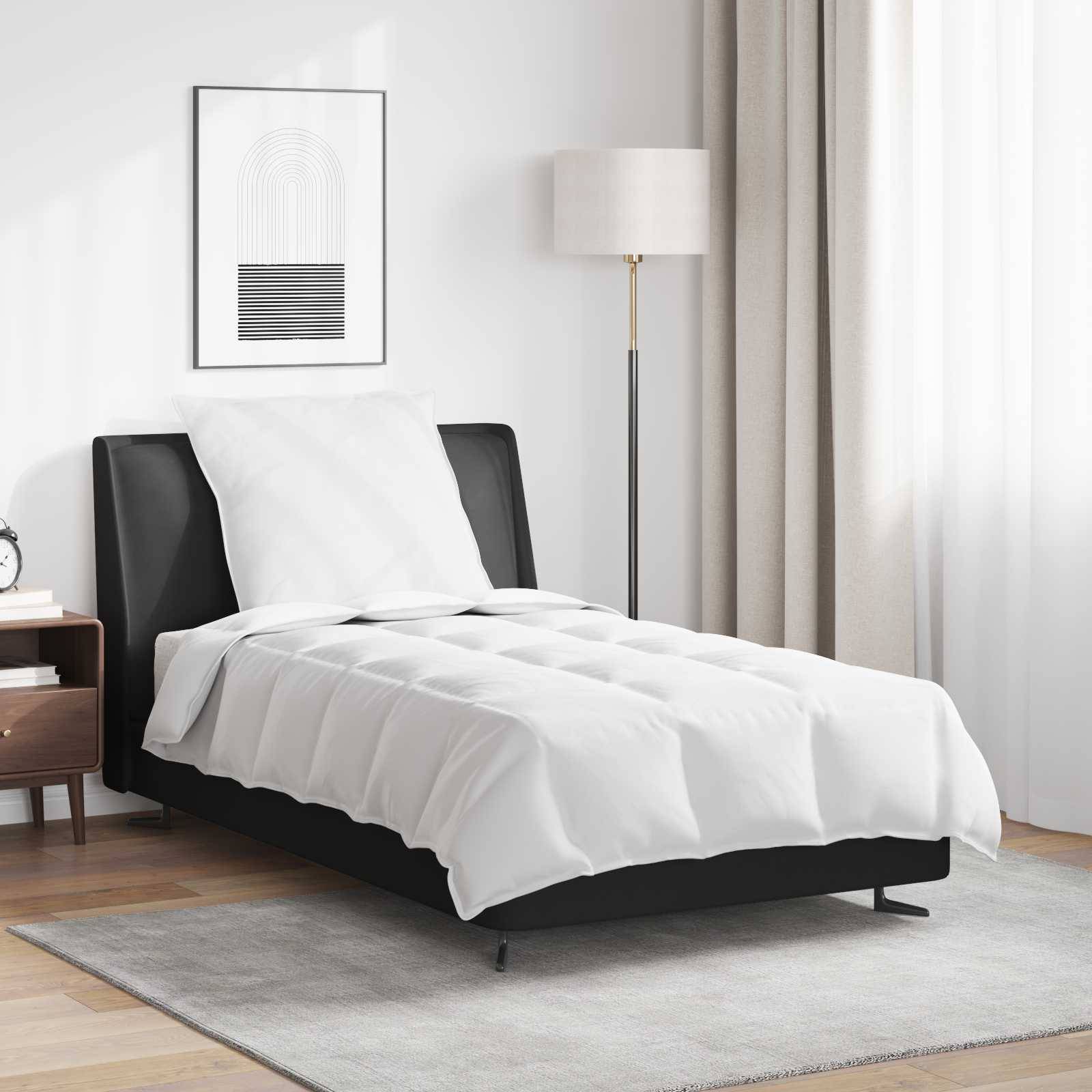 Ein minimalistisches Schlafzimmer zeigt ein aufgeräumtes Einzelbett mit einem weißen Bettdecken, einem Nachttisch, einer Stehlampe und einem geometrischen gerahmten Kunstwerk an der Wand.