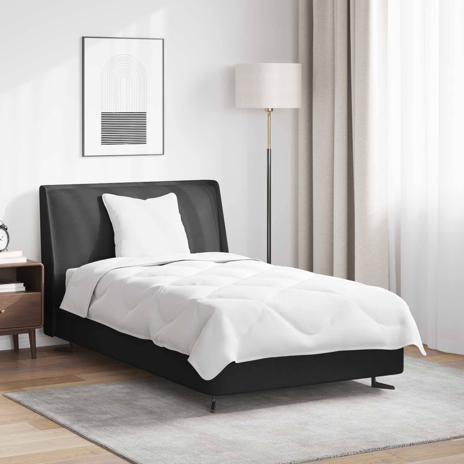 Ein ordentlich gemachtes Bett in einem modernen Schlafzimmer mit schwarzem Rahmen, weißer Bettwäsche, einem Nachttisch mit Büchern, einer Stehlampe und Wandkunst.