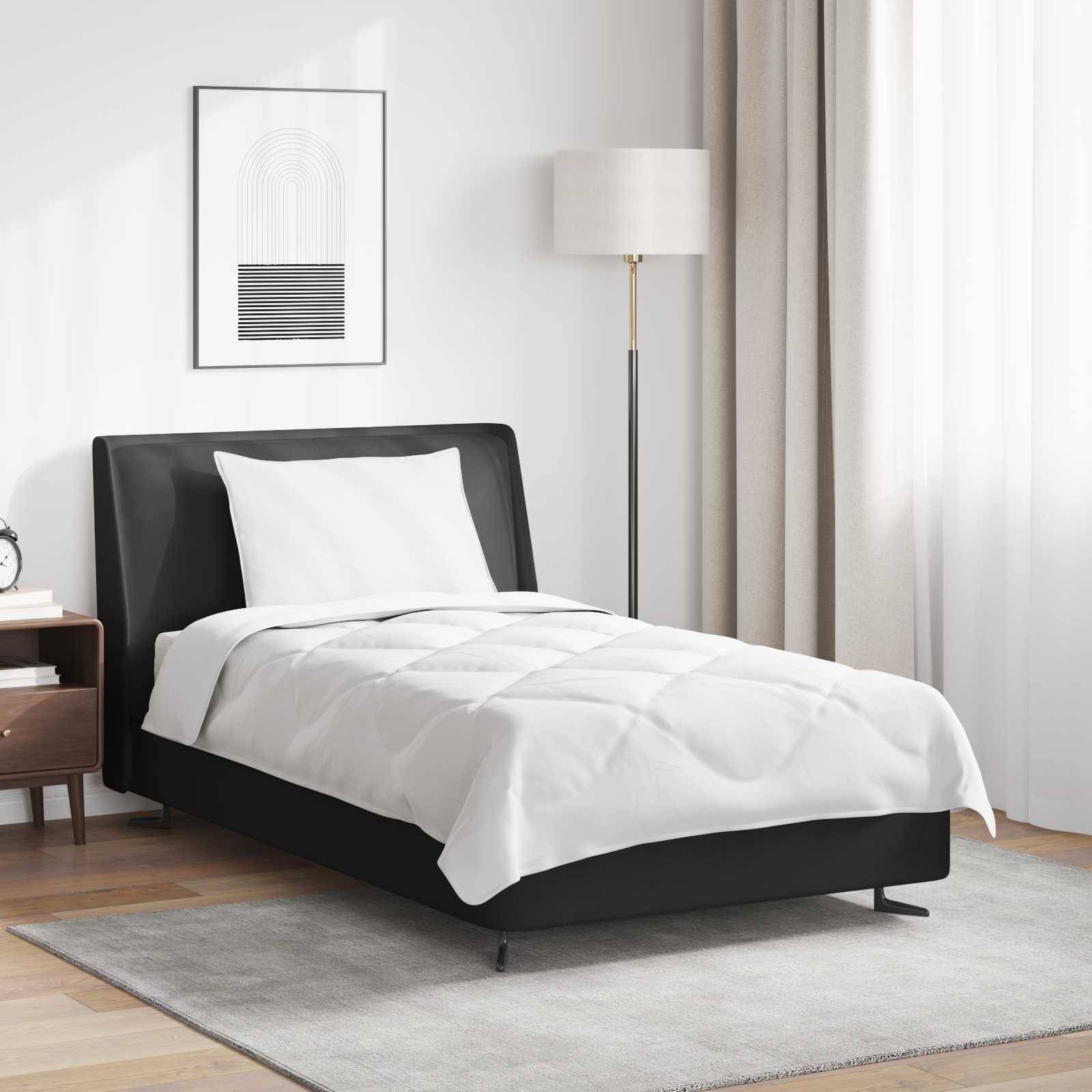 Ein modernes Schlafzimmer mit einem ordentlich bezogenen Einzelbett, das mit einem weißen Bettüberwurf ausgestattet ist, einer Lampe und Kunstwerk an der Wand sowie Holzfußboden.