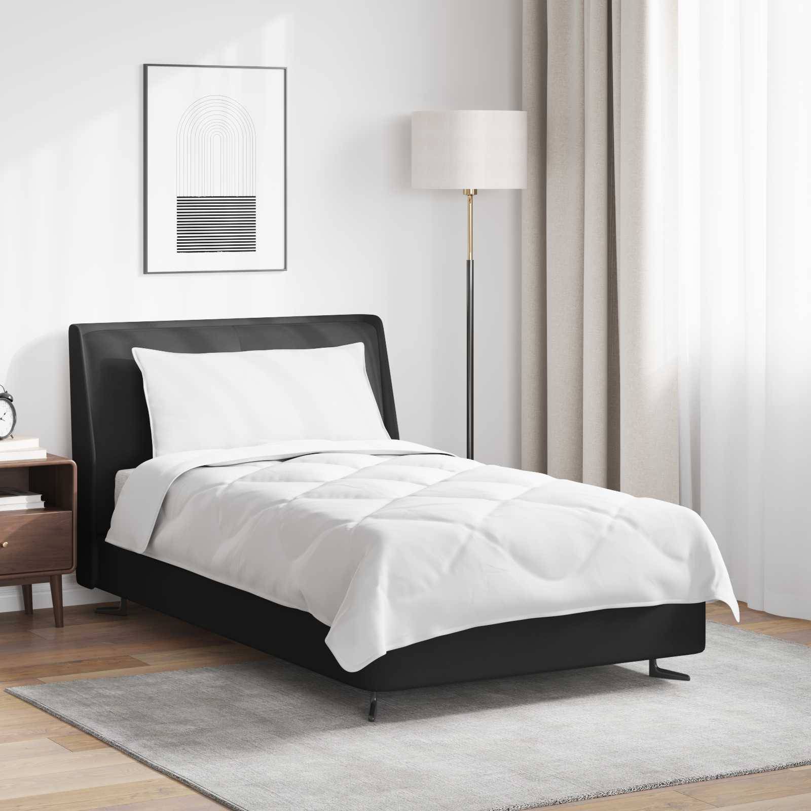 Ein modernes Schlafzimmer zeigt ein ordentlich gemachtes Bett mit einem schwarzen Rahmen, weißer Bettwäsche, einem Holznachttisch mit Büchern und einer hohen Stehlampe.