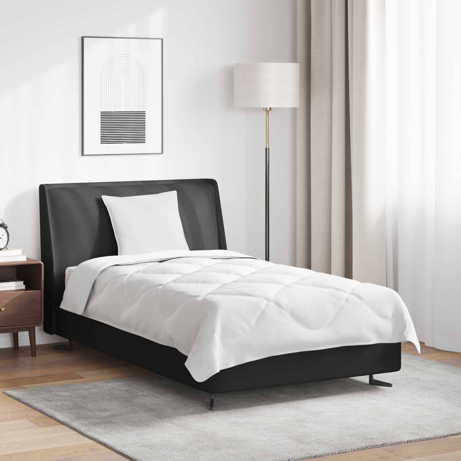 Ein aufgeräumtes Schlafzimmer mit einem schwarzen Bettgestell, weißer Bettwäsche, einer Stehlampe und einem gerahmten geometrischen Kunstwerk an der Wand. Beige Gardinen hängen daneben.