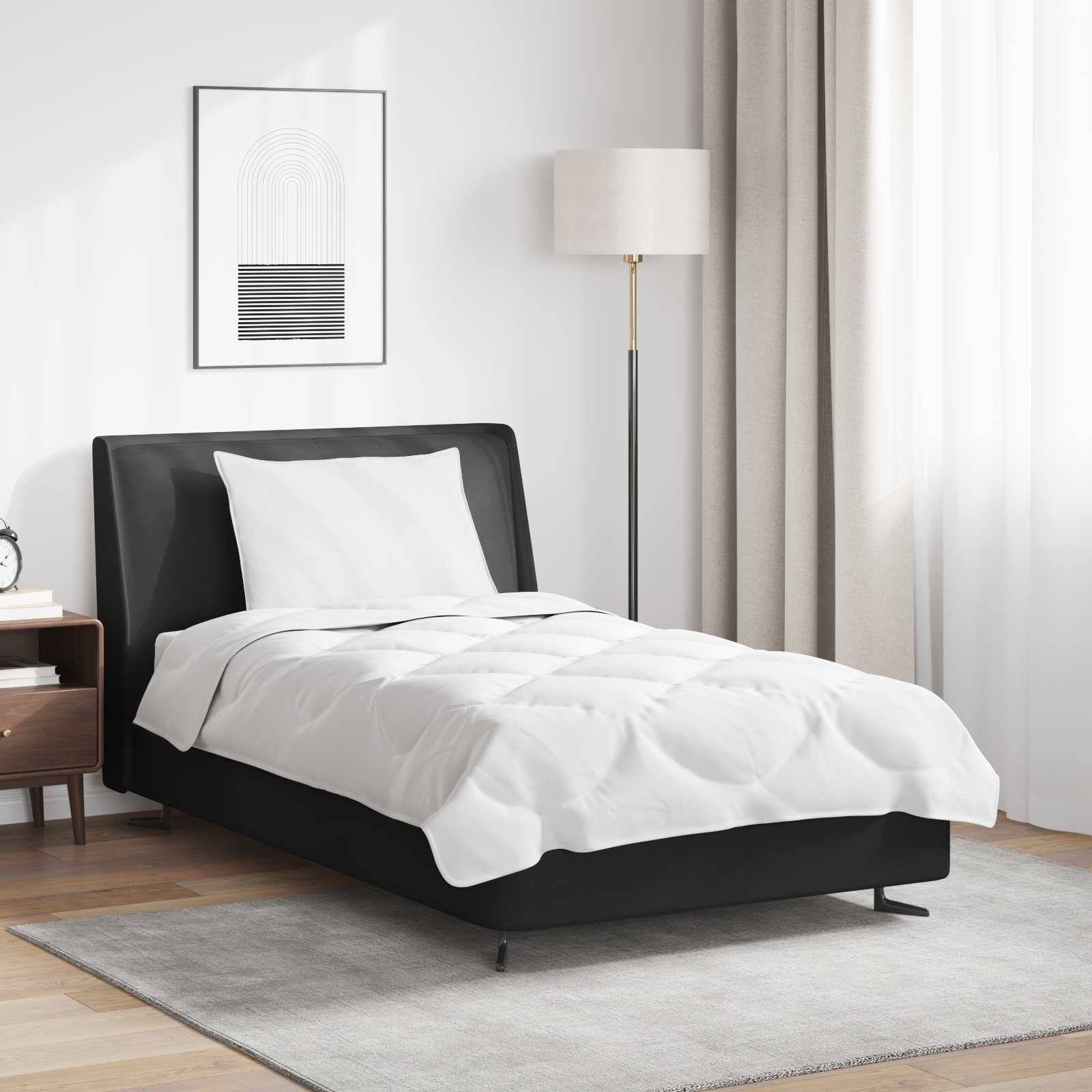 Ein modernes Schlafzimmer mit einem ordentlich gemachten Bett, das eine weiße Bettdecke und ein Kissen aufweist, eine Stehlampe und minimalistische Kunst an der Wand.