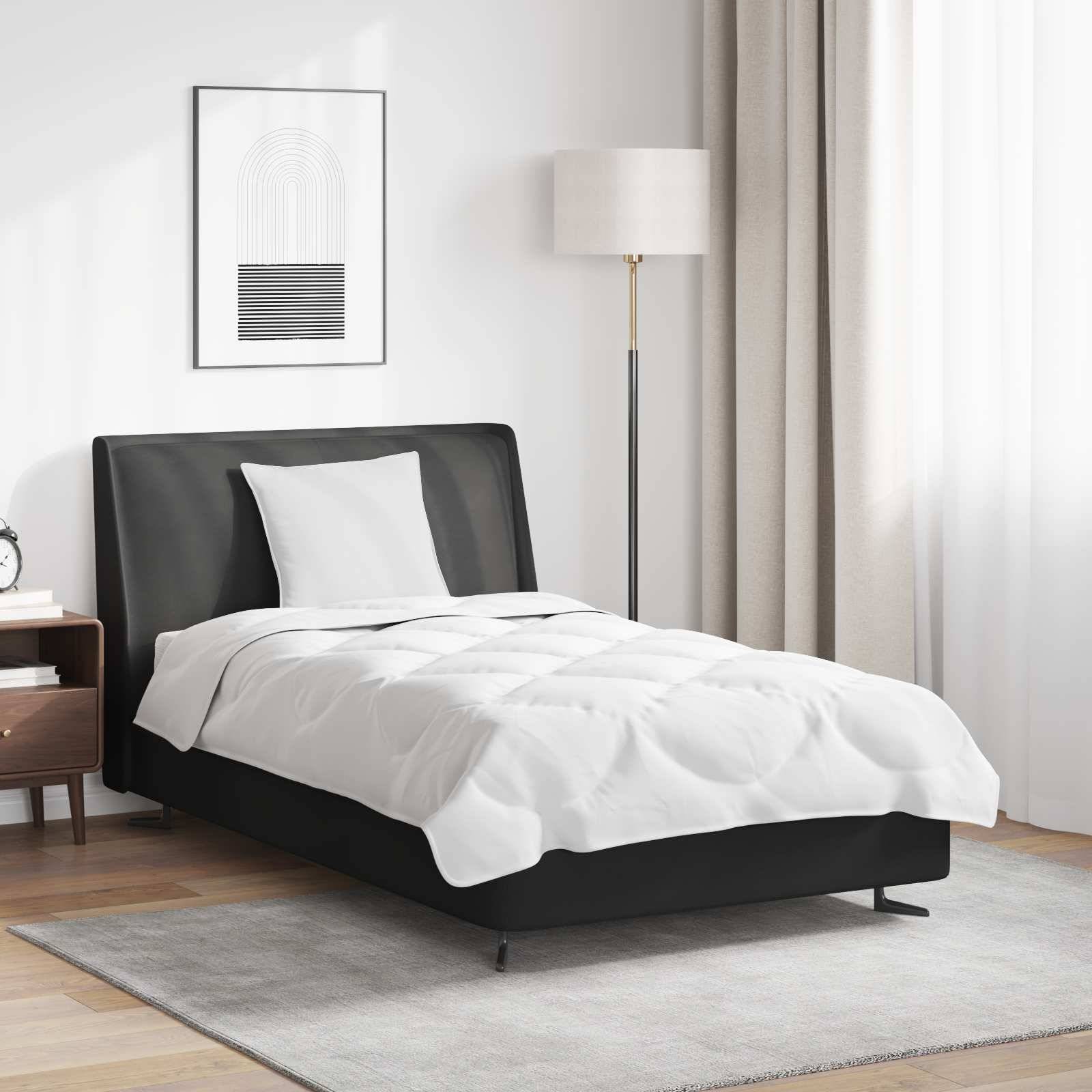 Ein ordentlich gemachtes Bett mit weißer Bettwäsche, schwarzem Kopfteil, einem Nachttisch mit Büchern, einem gerahmten abstrakten Kunstwerk und einer Stehlampe neben einem Fenster mit beigefarbenen Vorhängen.