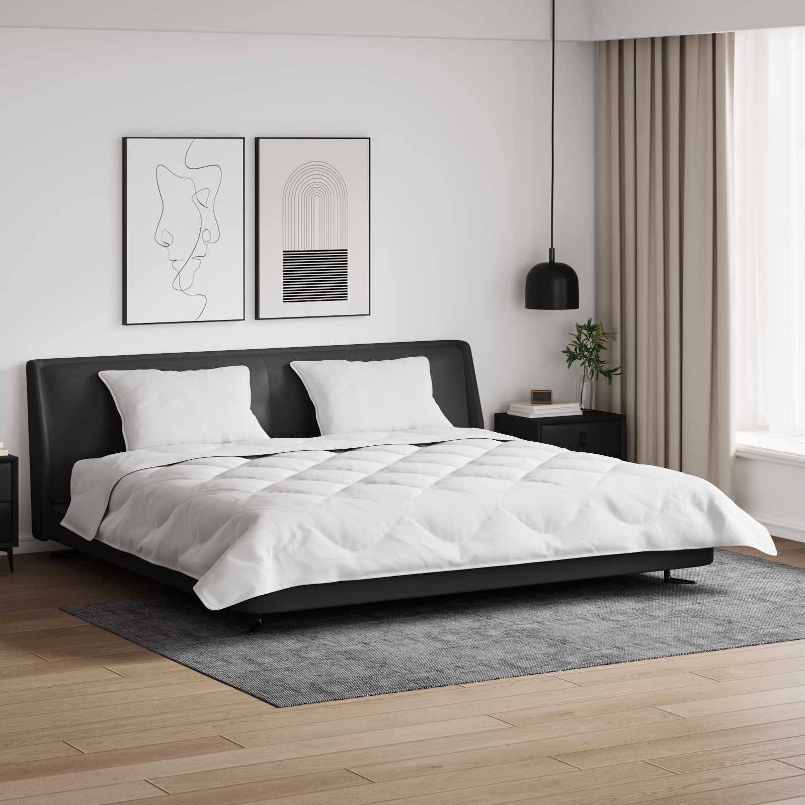 Ein modernes Schlafzimmer mit einem niedrigen, schwarzen Bettgestell und weißer Bettwäsche. Zwei abstrakte Kunstdrucke hängen über dem Bett, und eine schwarze Pendelleuchte befindet sich rechts davon.