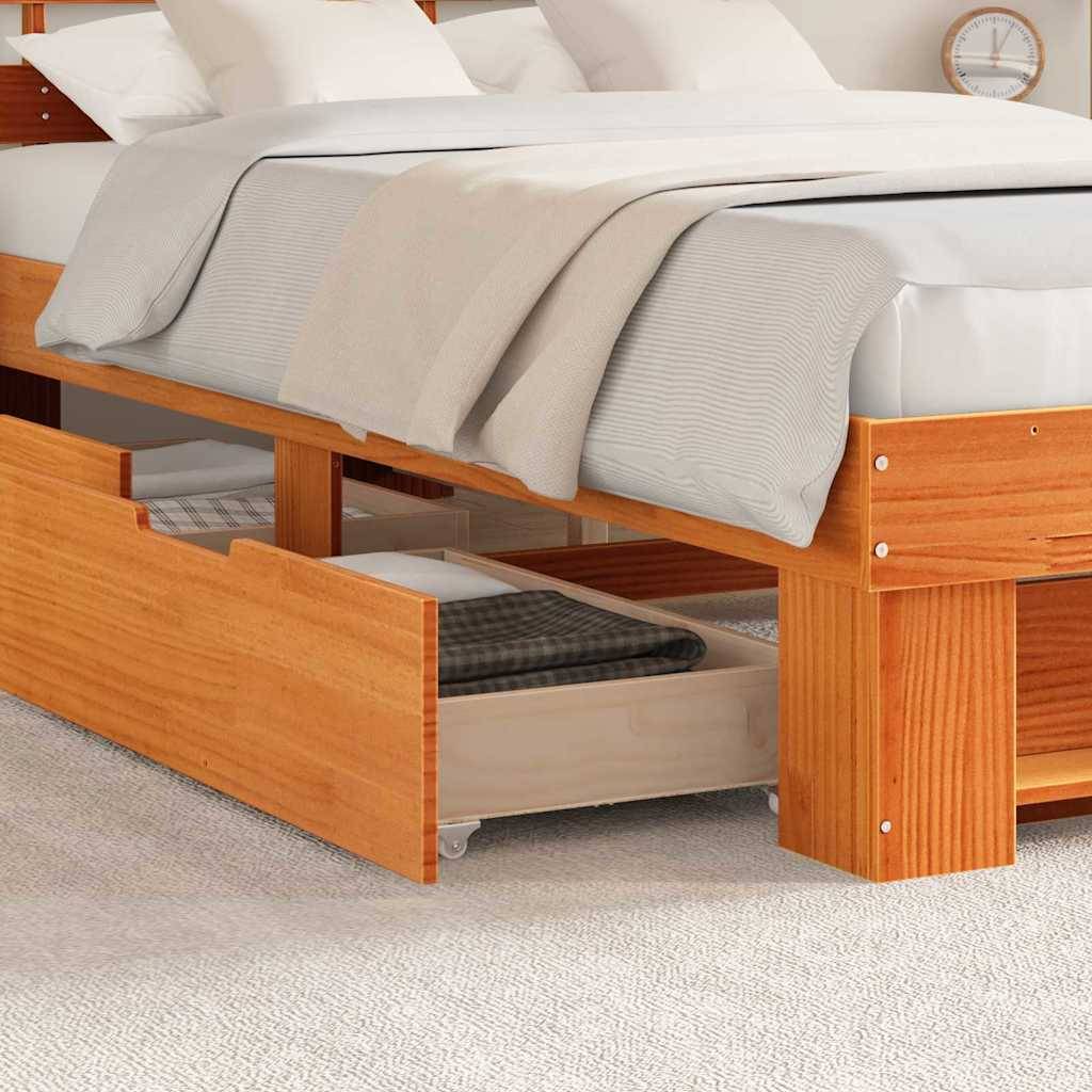 Ein Holzbett mit beigefarbener Bettwäsche, das Unterbett-Aufbewahrungsschubladen mit einer karierter Decke zeigt, auf einem hellbeigen Teppichboden.