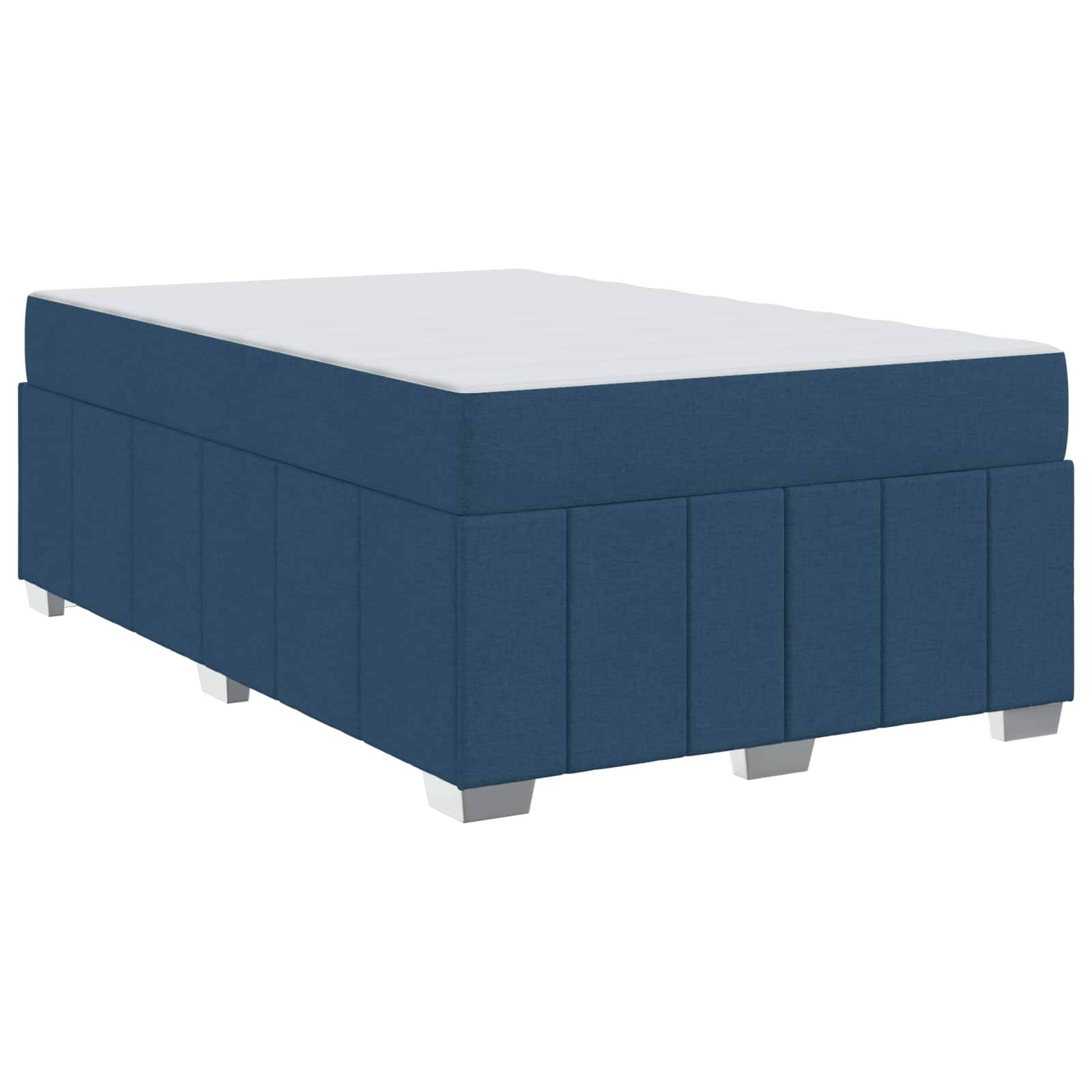 Ein blau gepolsterter Boxspringbett-Unterbau mit einer weißen Oberfläche, von einem niedrigen Winkel aus aufgenommen. Der Unterbau hat silberne Beine und ist für eine Matratze geeignet.